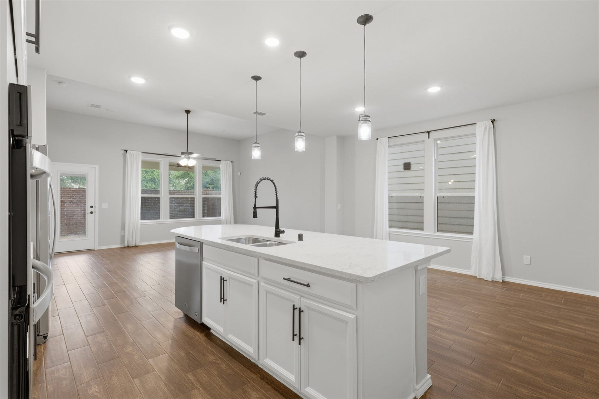 4028 Starbright Street, Houston, TX 77018 A close-up of the kitchen island highlights the sleek white countertops, under-mount double sink, and contemporary pendant lighting hanging overhead.