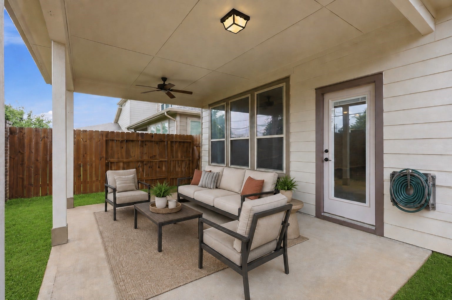 4028 Starbright Street, Houston, TX 77018 A covered concrete patio features a ceiling fan, flush-mount lighting, and large windows alongside a glass-paned backdoor.**Virtually staged