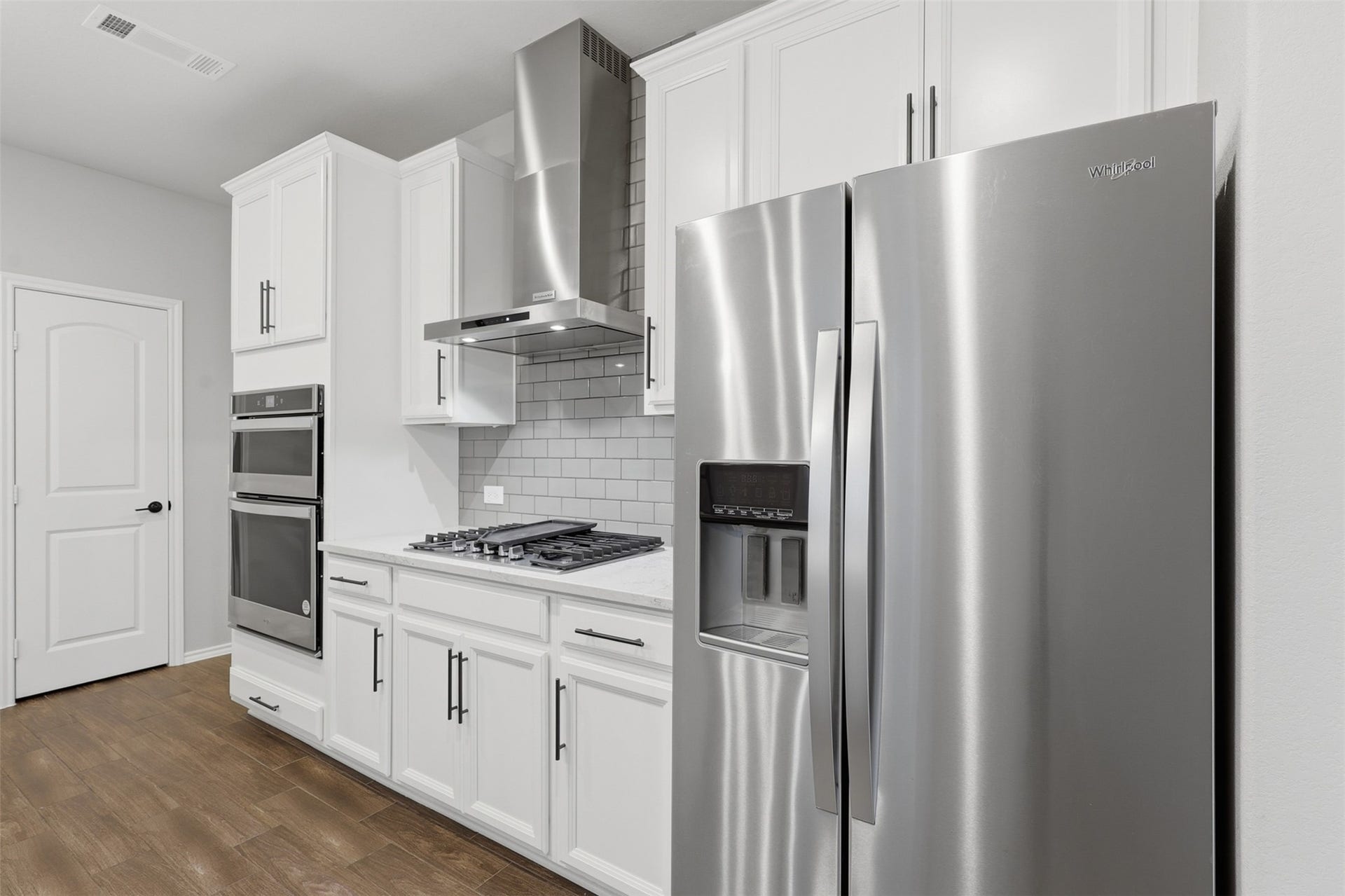 4028 Starbright Street, Houston, TX 77018 The functional workspace details a stainless steel range hood, classic gray subway tile backsplash, and matching white shaker cabinets.