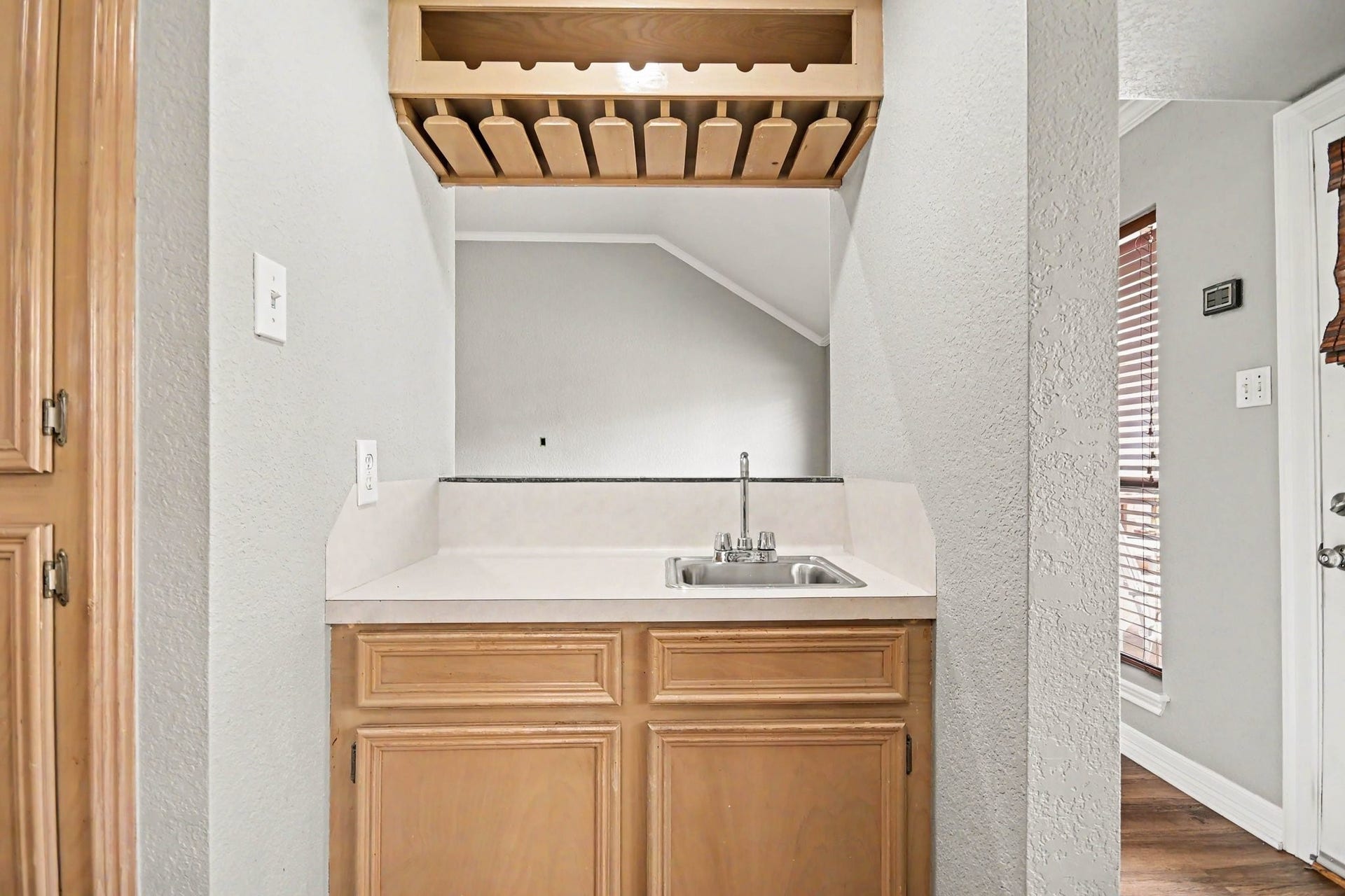 Built-in wet bar featuring a sink, countertop, and custom wood cabinetry