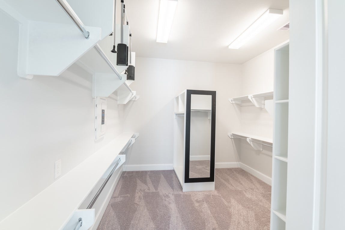 Primary closet is almost the size of a secondary bedroom with pull down racks, a dressing mirror and nice well constructed shelving.