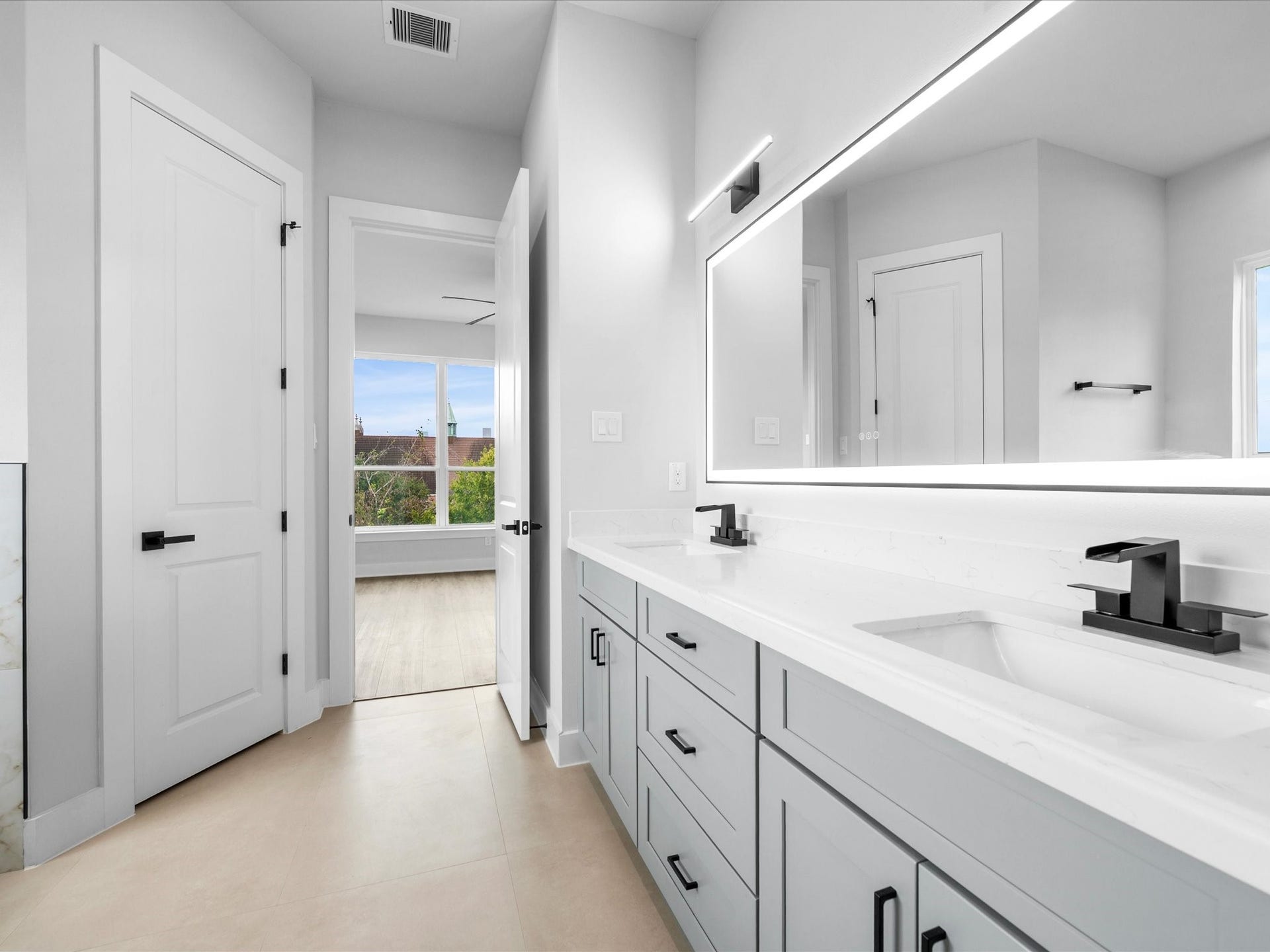 120 Estelle Street, Houston, TX 77003 Contemporary lighting, elegant finishes, and clean lines give the primary bathroom vanity a polished look that complements the home's sophisticated design.