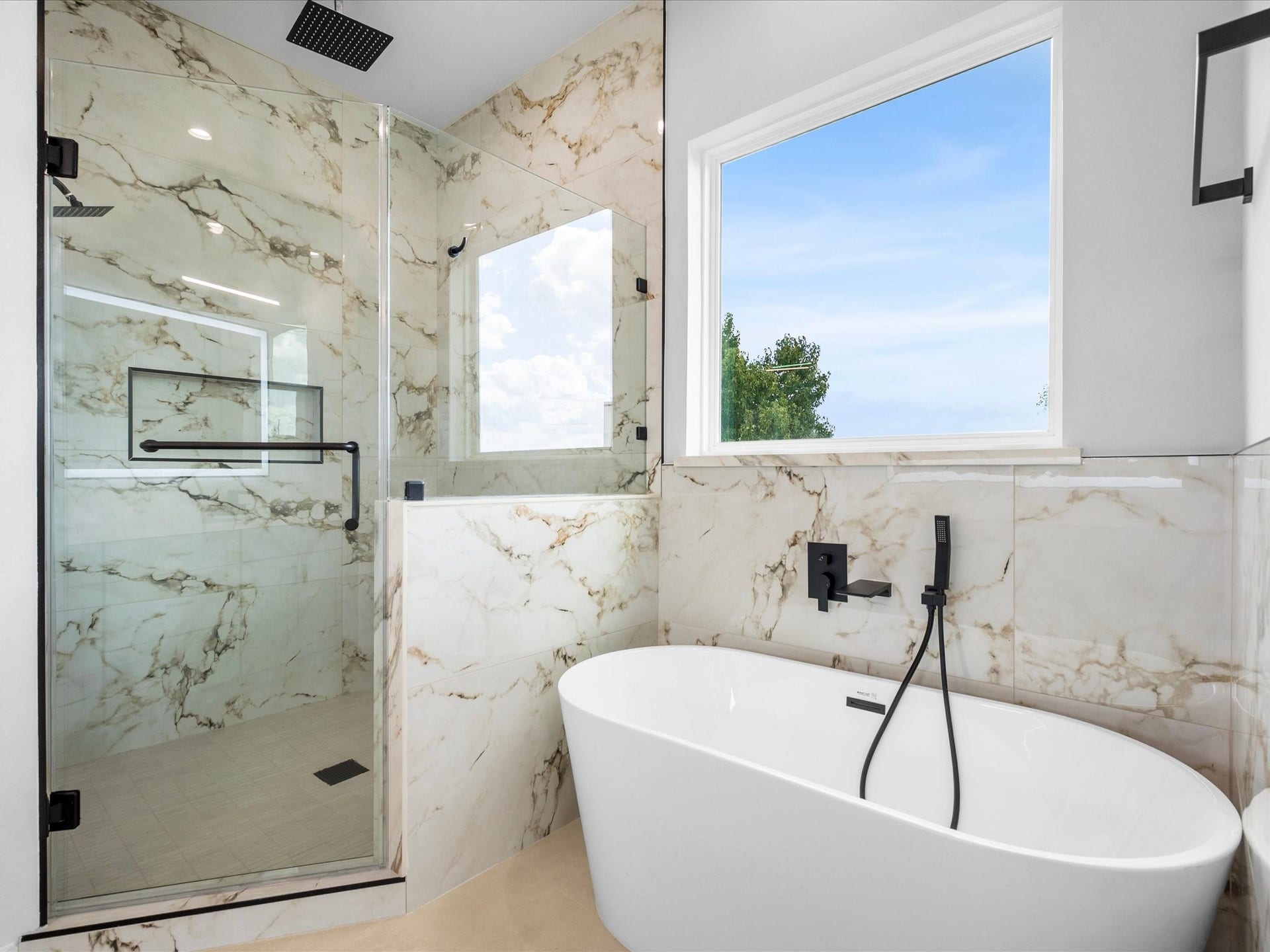 120 Estelle Street, Houston, TX 77003 A beautiful soaking tub creates an inviting place to unwind, while refined tilework and contemporary fixtures elevate the primary bathroom.