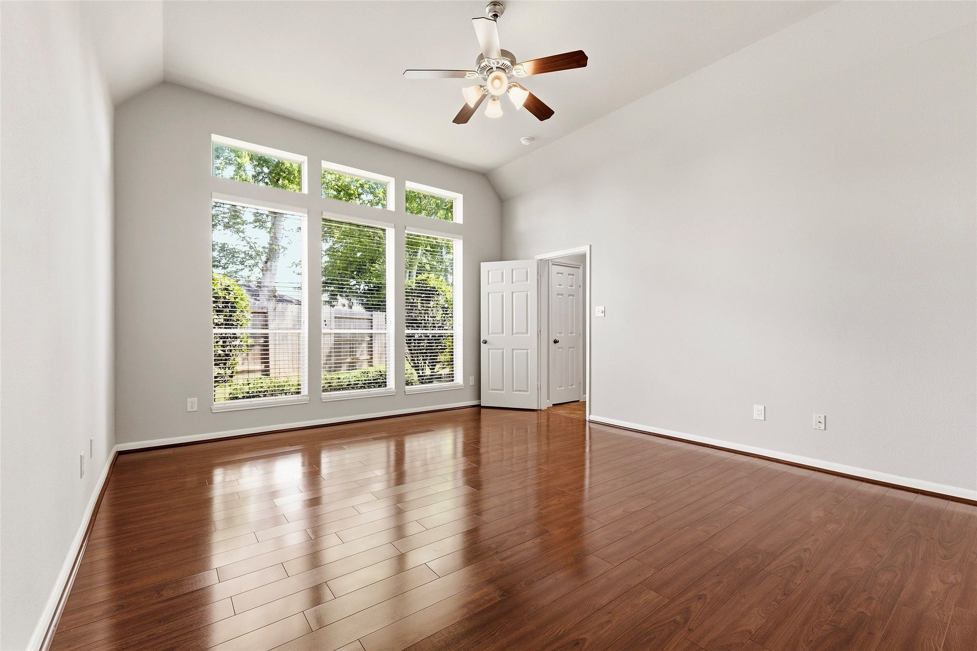 Spacious primary bedroom with high ceilings, large windows for natural light, and beautiful wood flooring, perfect for a cozy and inviting atmosphere.