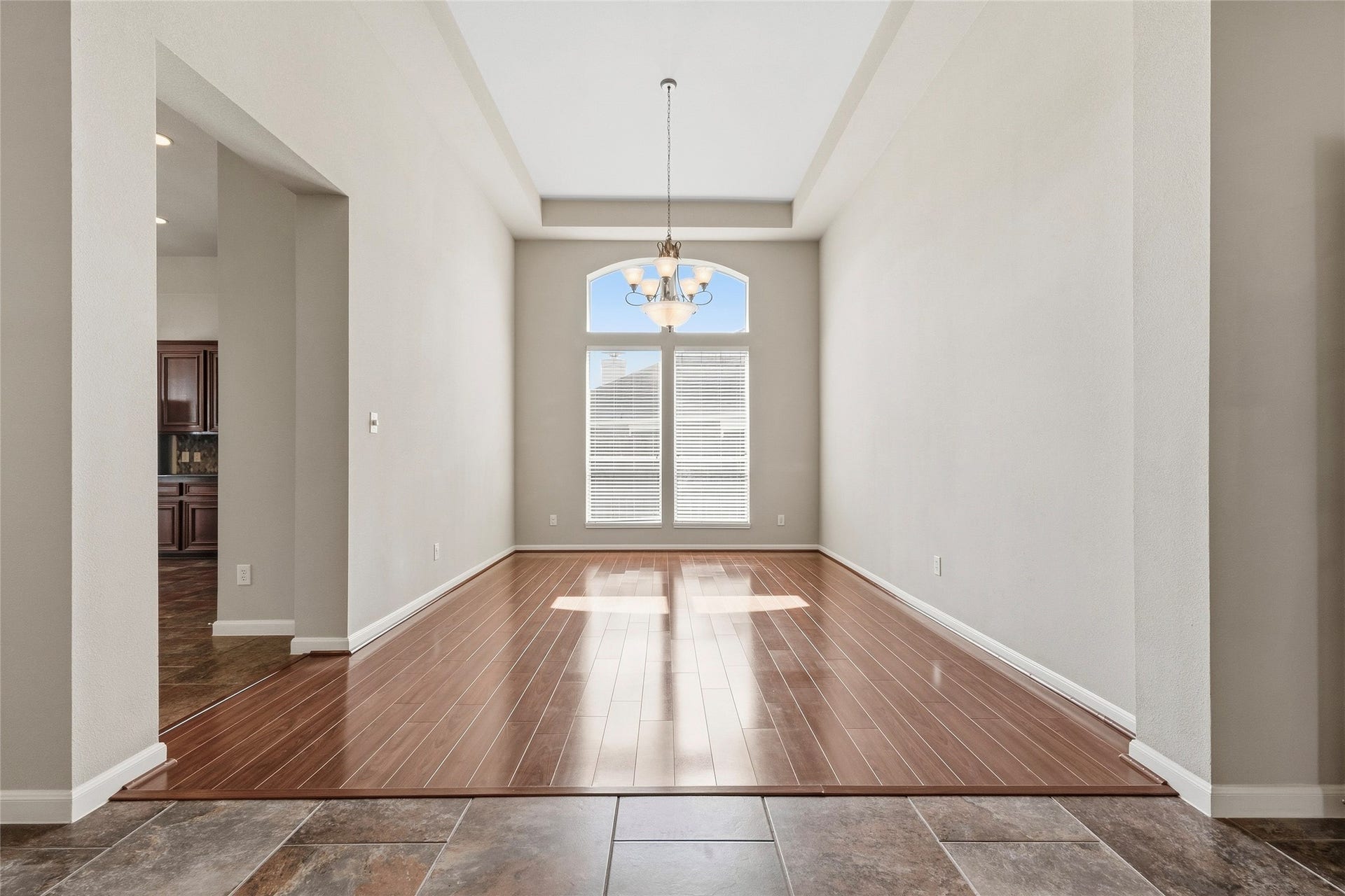 Elegant dining area with high ceilings, rich wood flooring, and abundant natural light from large windows, perfect for entertaining.