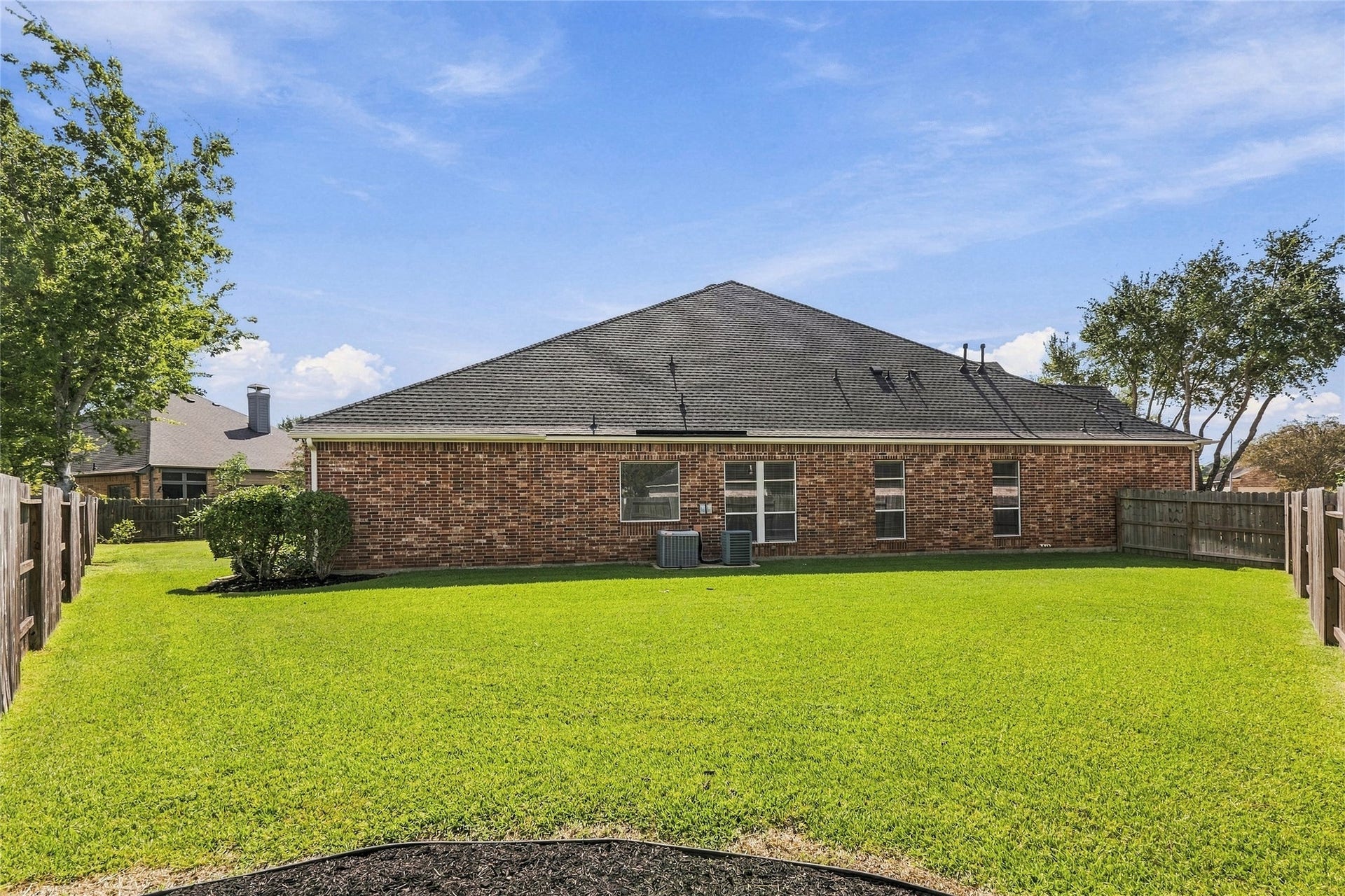 Spacious backyard with lush green lawn and privacy fencing, perfect for outdoor activities.