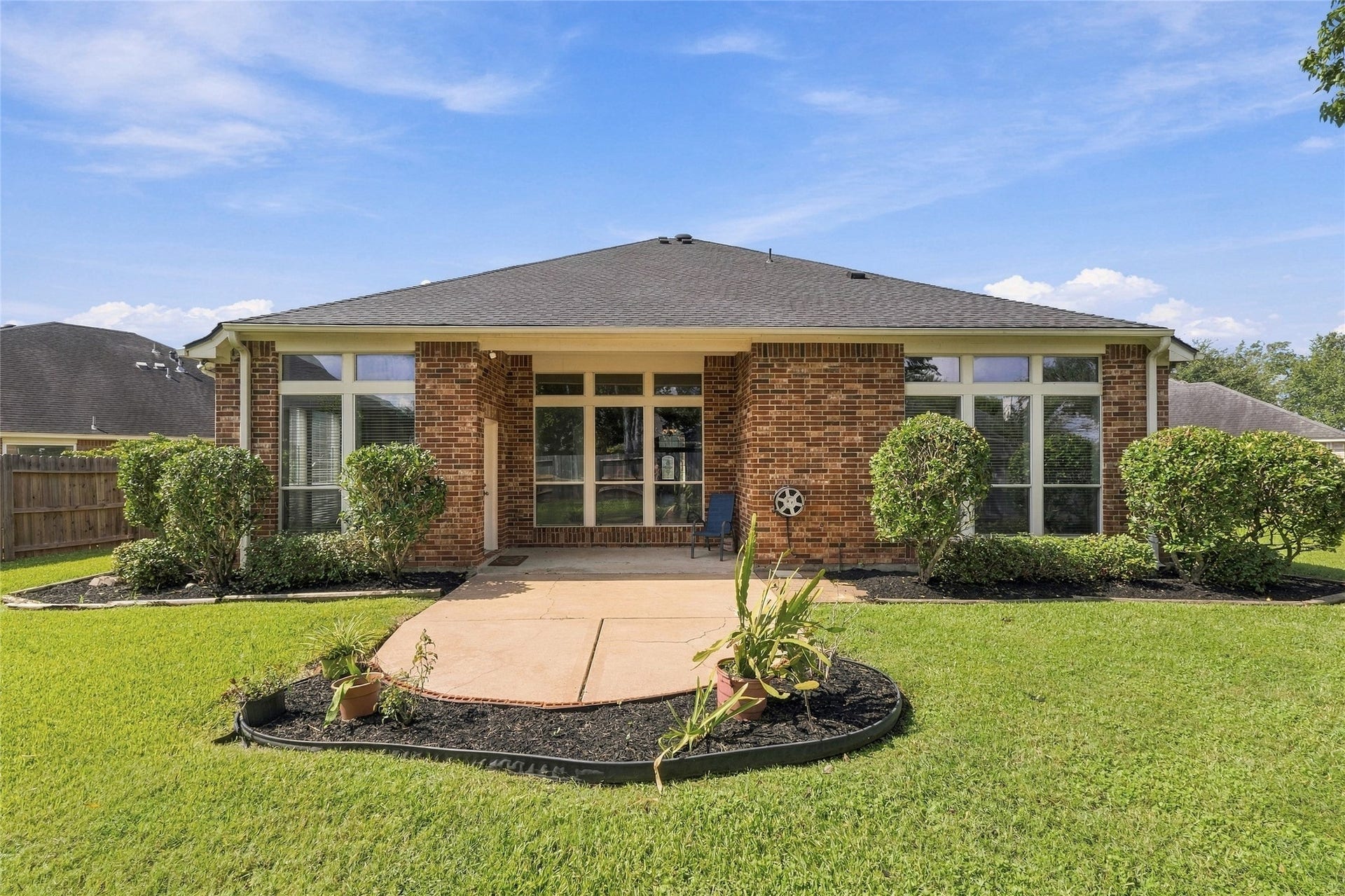 Charming brick home with spacious patio and manicured lawn, perfect for outdoor enjoyment.