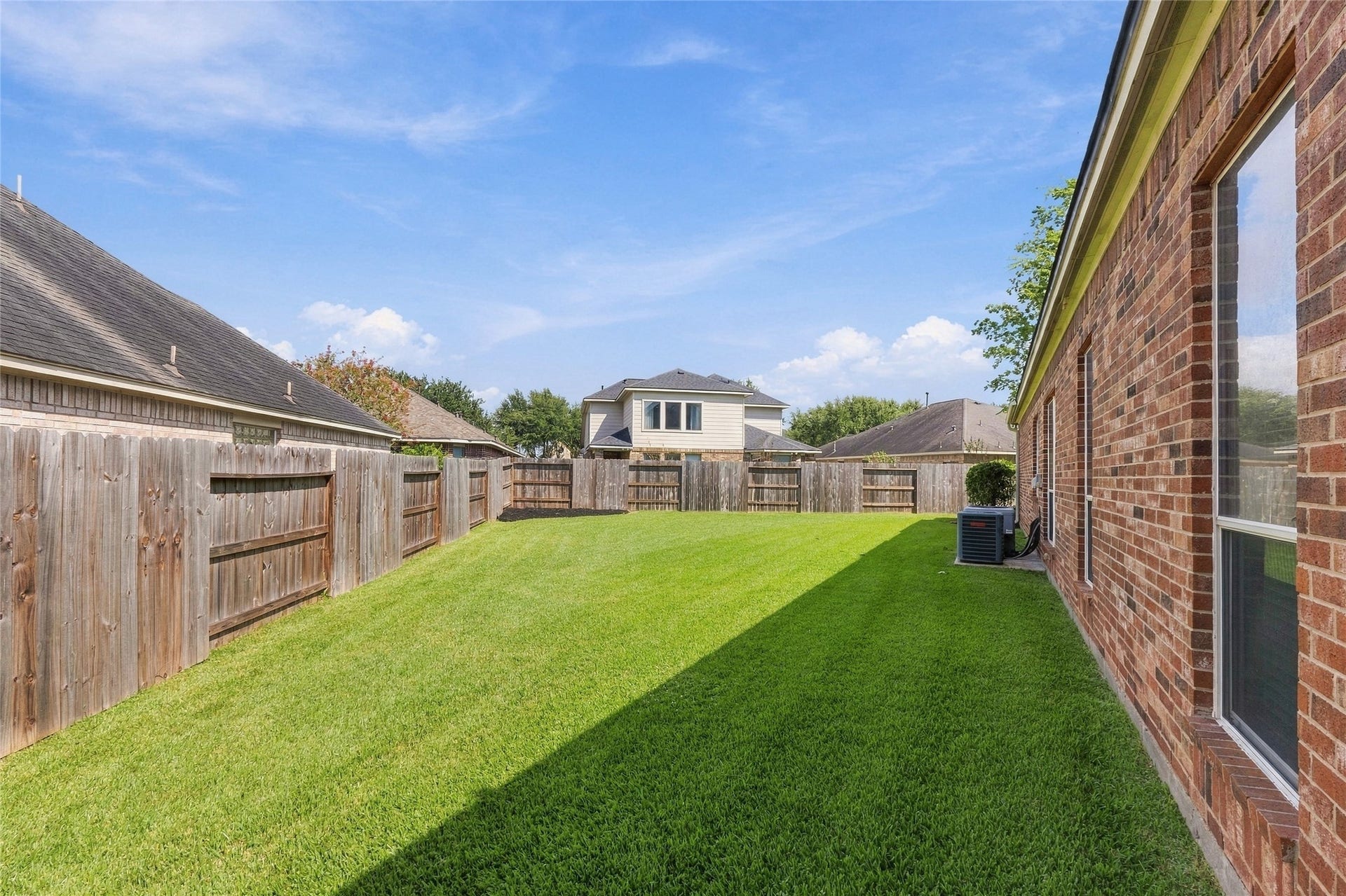 Expansive backyard with lush green lawn, perfect for outdoor activities and entertaining, bordered by a sturdy wooden fence for privacy.