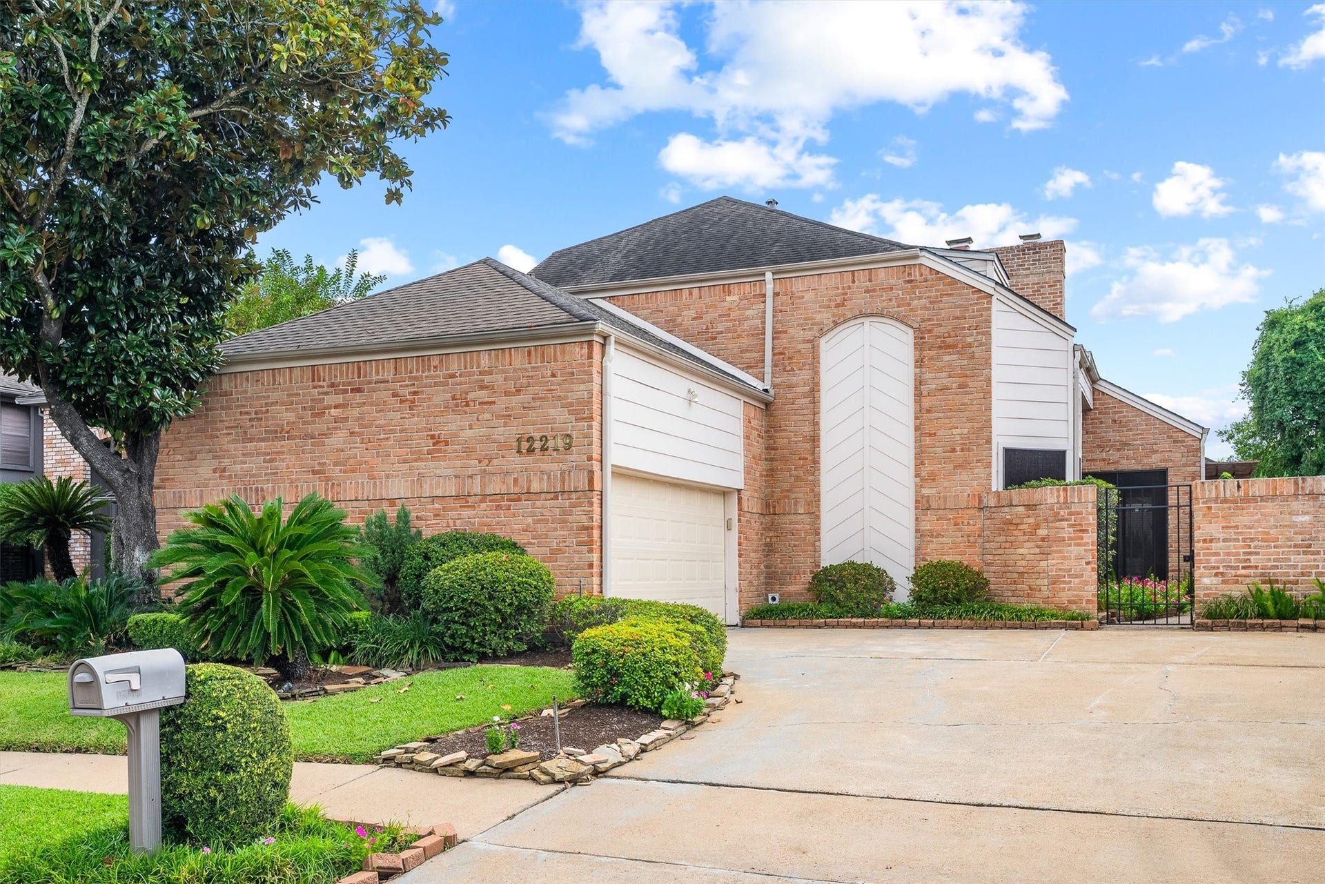 12219 Ravenmoor Drive, Houston, TX 77077 Charming brick home with a welcoming driveway and lush landscaping, offering a blend of privacy and curb appeal.