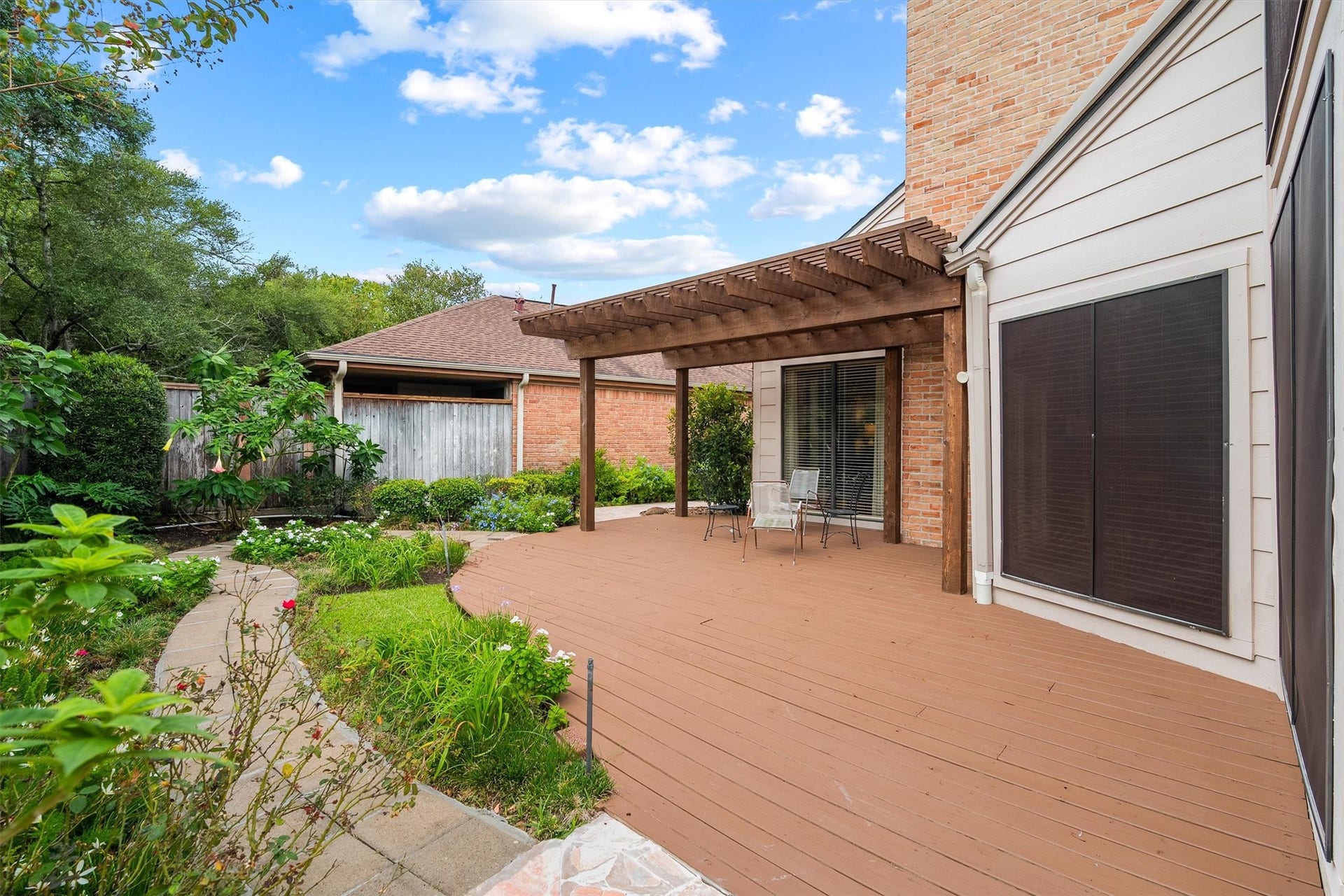 12219 Ravenmoor Drive, Houston, TX 77077 Enjoy a beautifully landscaped backyard featuring a spacious wooden deck, inviting pergola, and charming garden pathways; an ideal outdoor retreat for relaxing or entertaining.