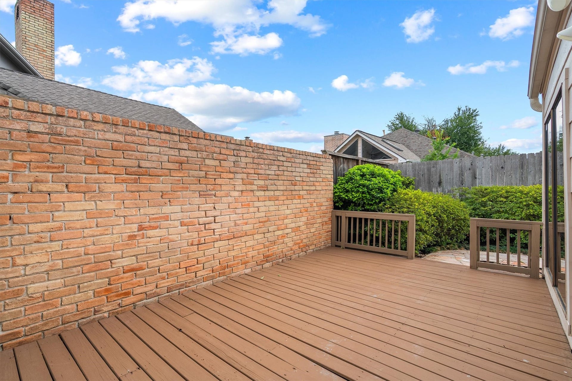 12219 Ravenmoor Drive, Houston, TX 77077 Nice private patio with a wooden deck, surrounded by a brick wall and lush greenery, perfect for outdoor relaxation.