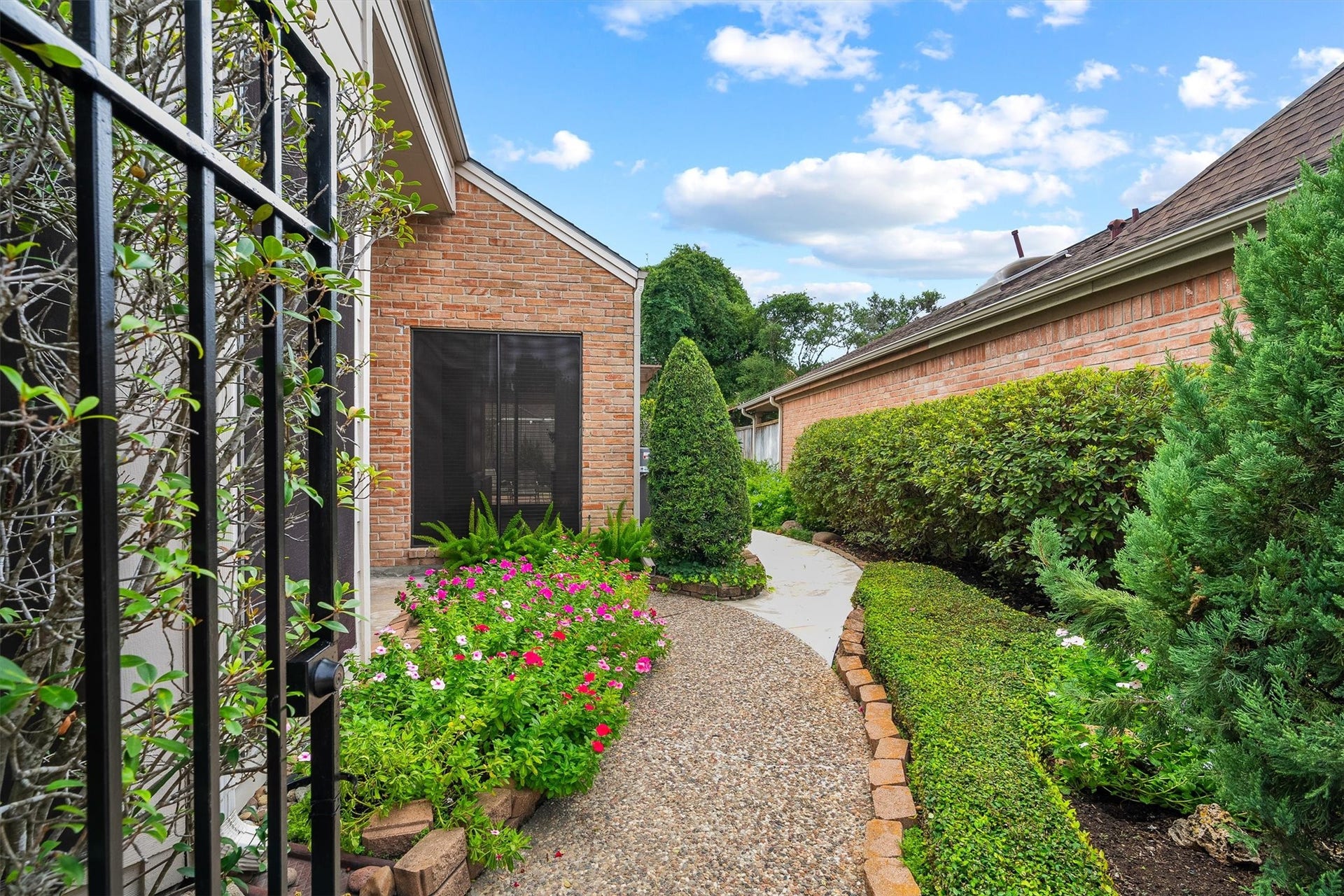 12219 Ravenmoor Drive, Houston, TX 77077 Nice pathway leads through a beautifully landscaped garden with vibrant flowers and lush greenery, enhancing the homes inviting brick exterior.