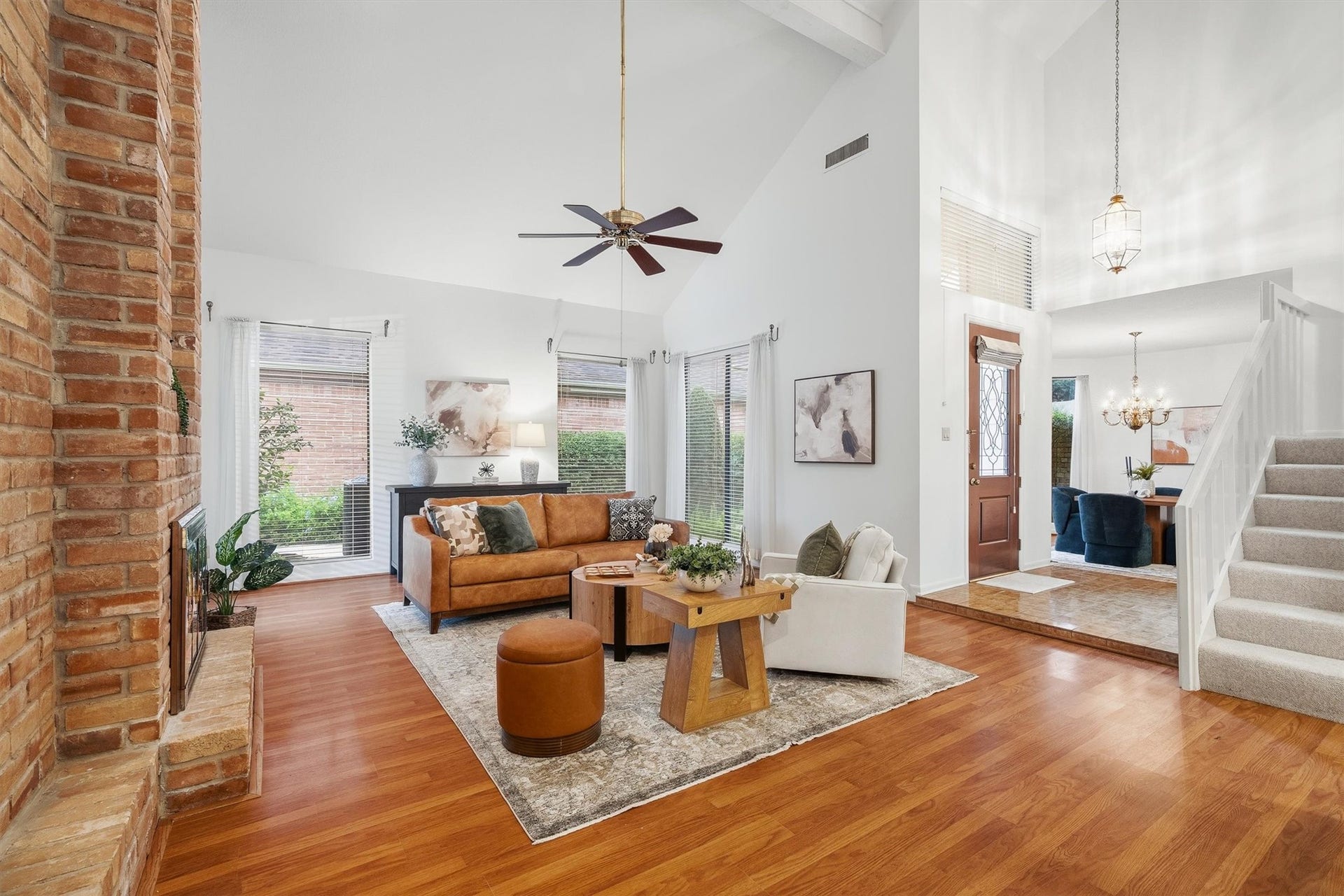 12219 Ravenmoor Drive, Houston, TX 77077 Bright and inviting living space featuring a vaulted ceiling, cozy brick fireplace, and elegant hardwood floors, seamlessly flowing into the dining area.