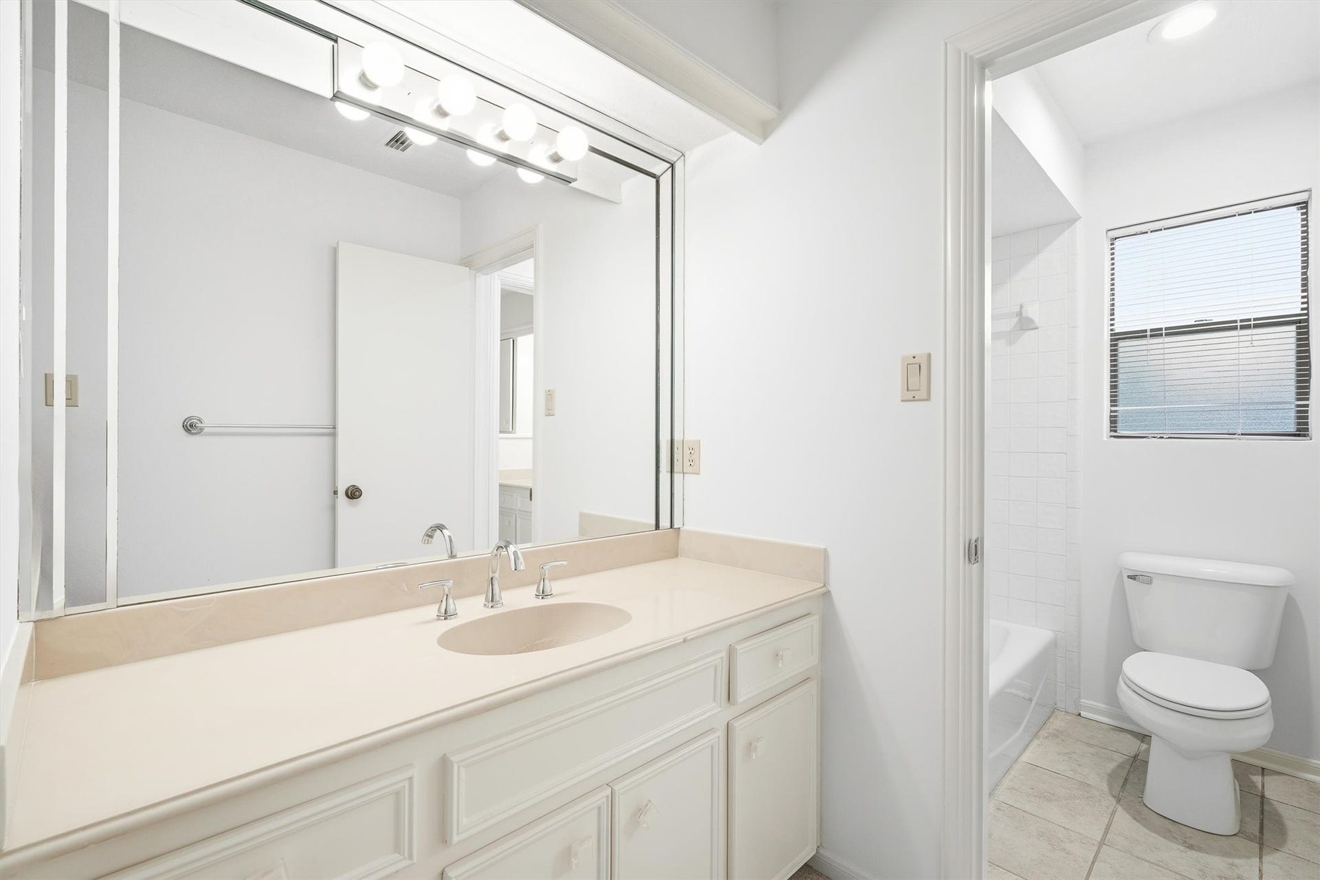 12219 Ravenmoor Drive, Houston, TX 77077 Bright and spacious bathroom featuring a large vanity with ample counter space, modern fixtures, and a sleek mirror, complemented by a tiled shower and natural light from the window.