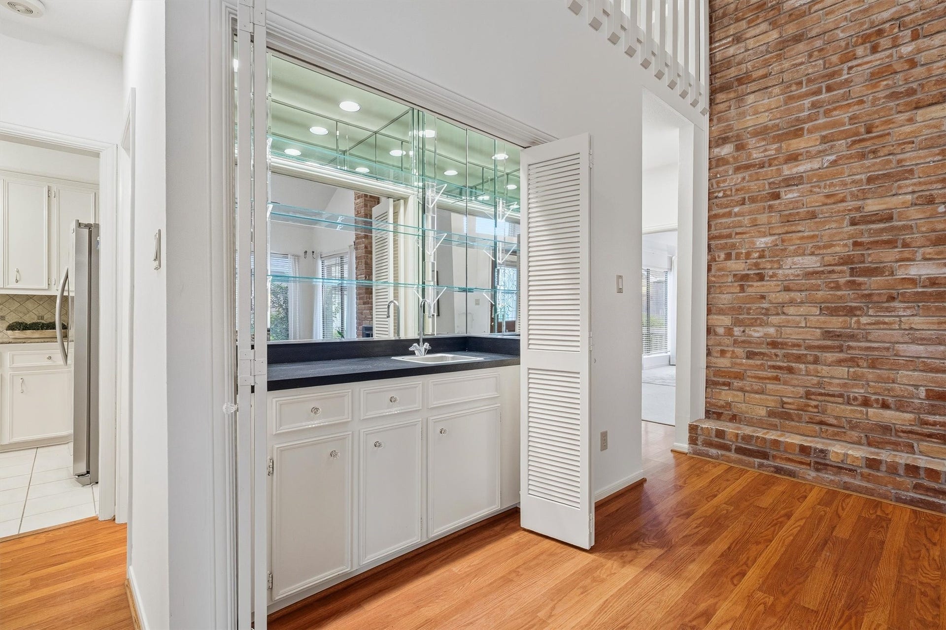12219 Ravenmoor Drive, Houston, TX 77077 Elegant wet bar with sleek cabinetry and mirrored shelving, perfect for entertaining in style.