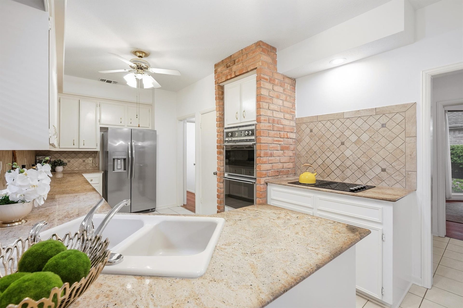 12219 Ravenmoor Drive, Houston, TX 77077 Charming kitchen with a spacious layout featuring modern stainless steel appliances, elegant granite countertops, and a cozy brick accent wall with built-in ovens.