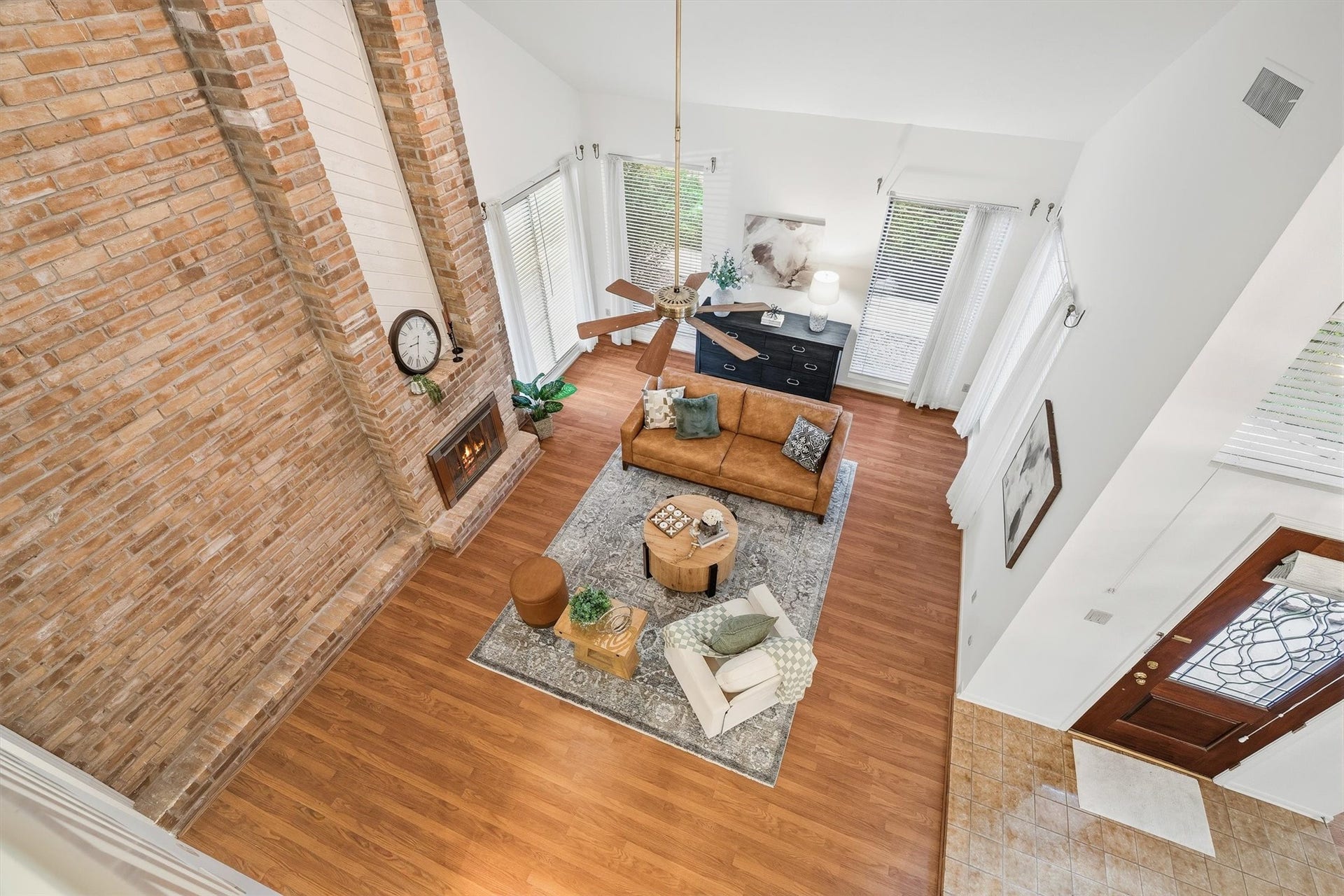 12219 Ravenmoor Drive, Houston, TX 77077 Experience a stunning open-concept living room with soaring ceilings, a striking brick fireplace, and abundant natural light, perfect for relaxation and entertaining.
