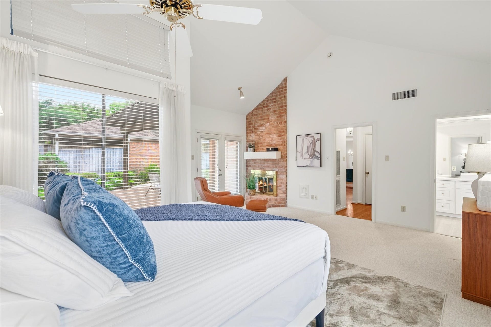 12219 Ravenmoor Drive, Houston, TX 77077 Spacious primary bedroom with a vaulted ceiling, cozy brick fireplace, and large windows offering plenty of natural light.