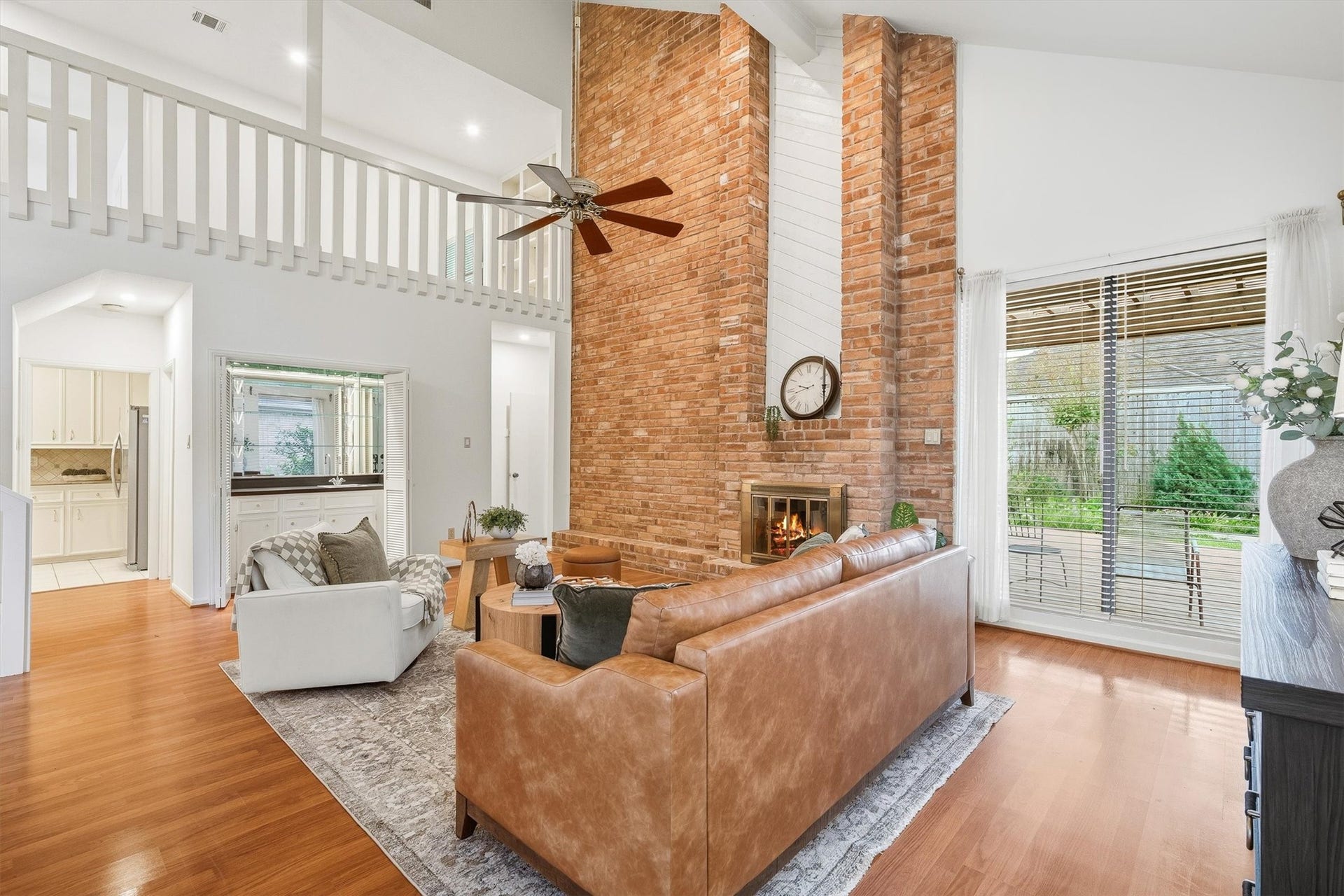 12219 Ravenmoor Drive, Houston, TX 77077 Spacious living area with a striking brick fireplace, high ceilings, and abundant natural light from large windows that overlook a serene backyard.