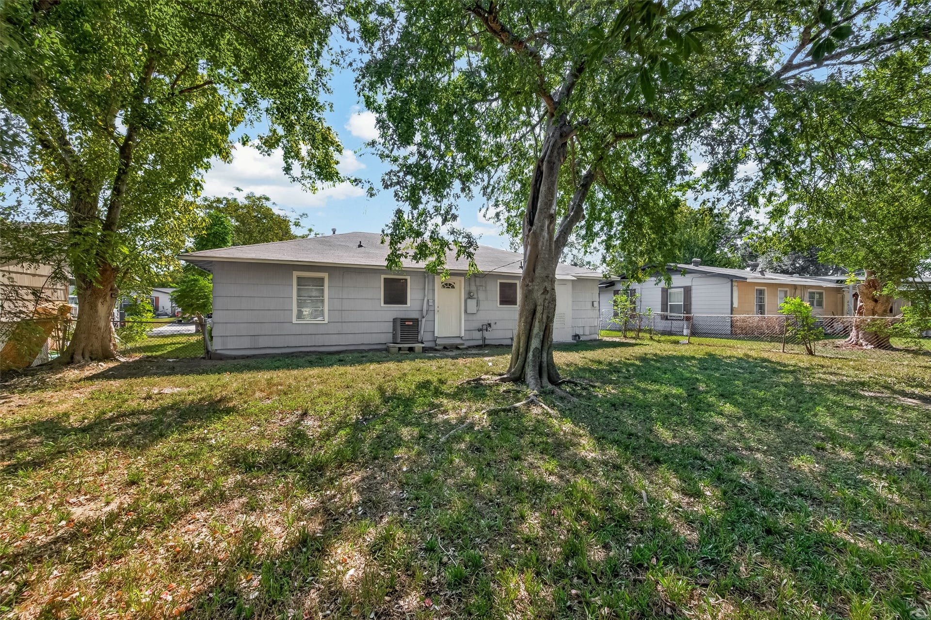 5935 Beldart Street, Houston, TX 77033 Backyard with large shade trees and open lawn.