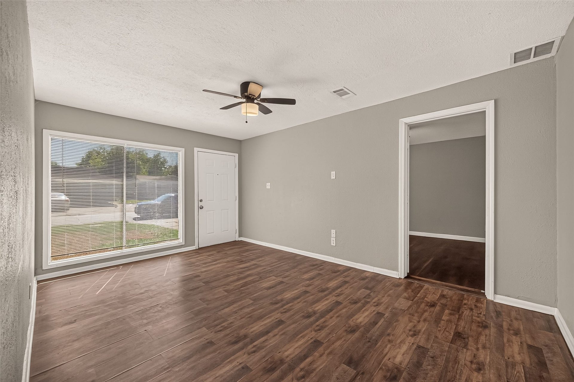 5935 Beldart Street, Houston, TX 77033 Living room, unfurnished, with large front window and ceiling fan.