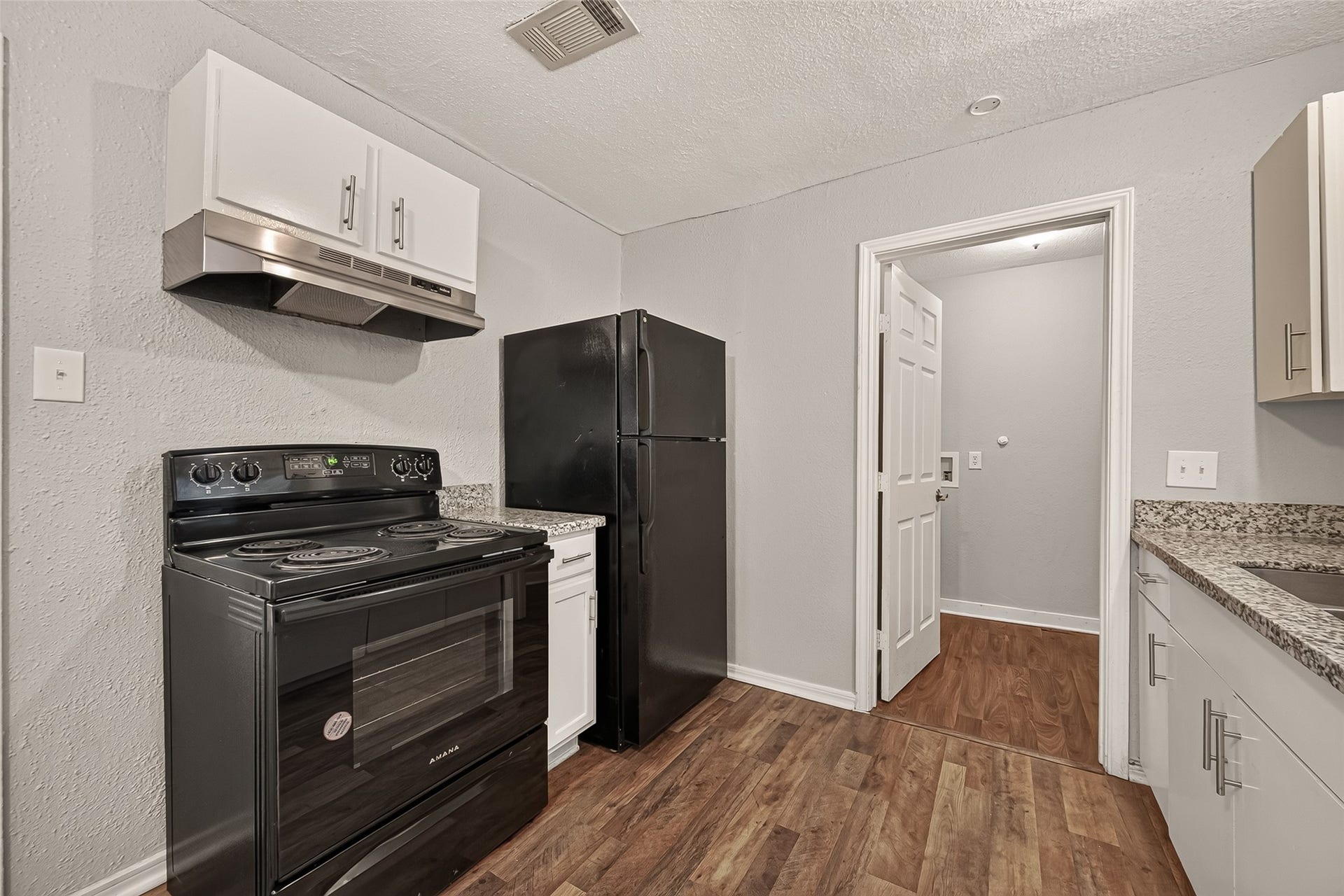 5935 Beldart Street, Houston, TX 77033 Kitchen with granite countertops, black appliances, and access to the utility room.