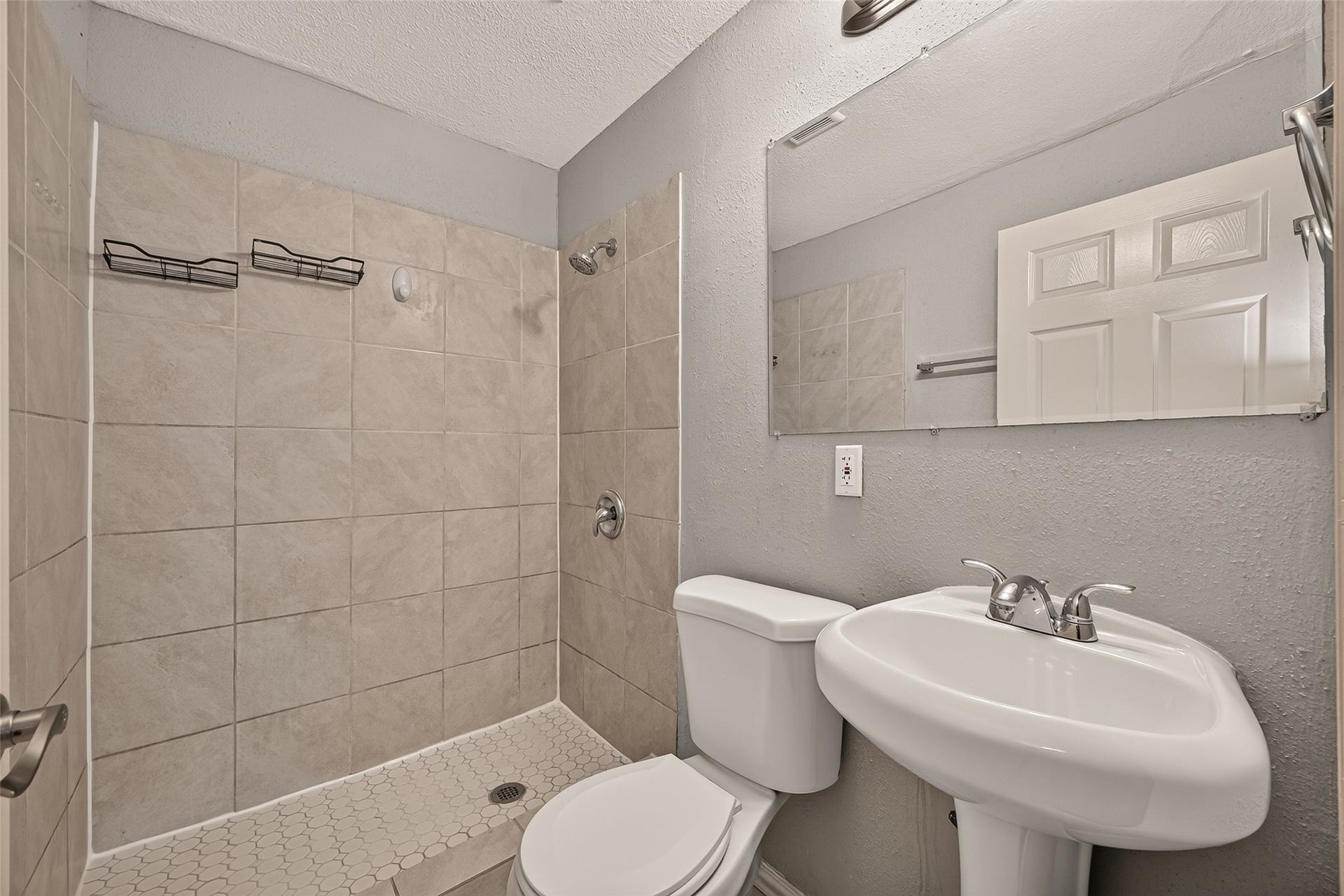 5935 Beldart Street, Houston, TX 77033 Primary en-suite bath with tiled walk-in shower, tile flooring, and pedestal sink.