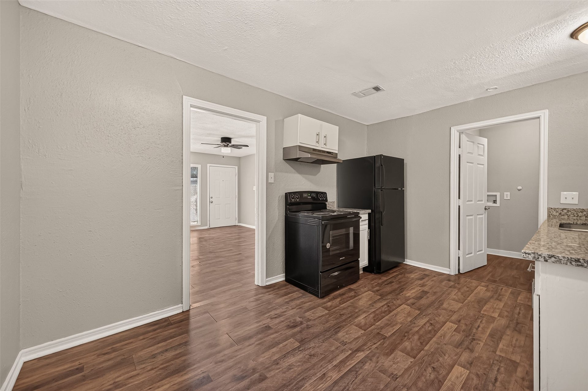 5935 Beldart Street, Houston, TX 77033 Kitchen with refrigerator and range, with view through to the living room.