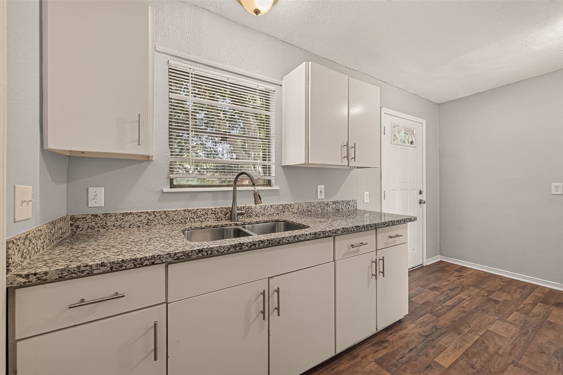 5935 Beldart Street, Houston, TX 77033 Kitchen sink under the window, with white cabinets and granite countertops.