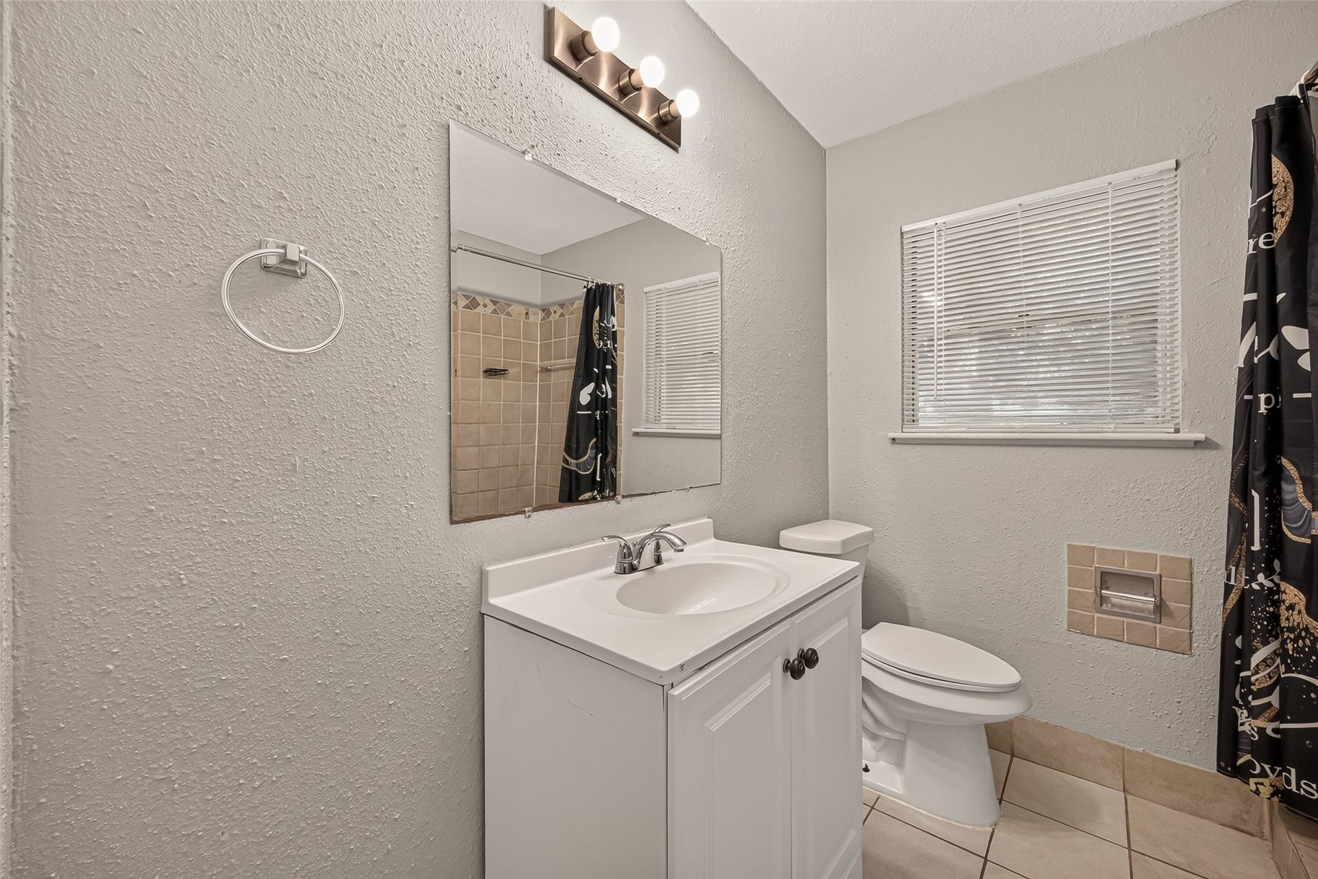 5935 Beldart Street, Houston, TX 77033 Hall bath with white vanity, tile flooring, and window.