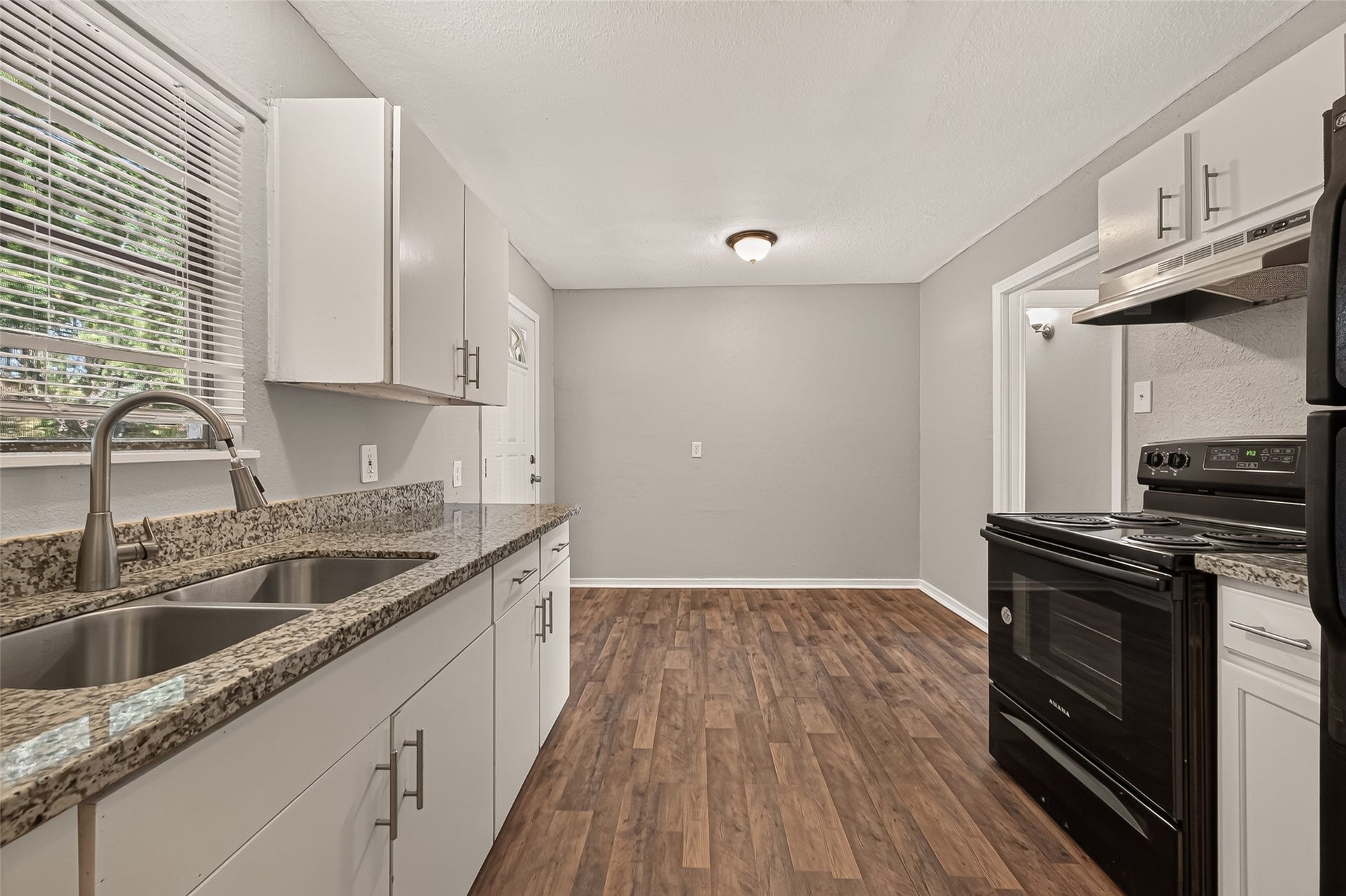 5935 Beldart Street, Houston, TX 77033 Kitchen, unfurnished, with granite countertops and view to the eat-in area.