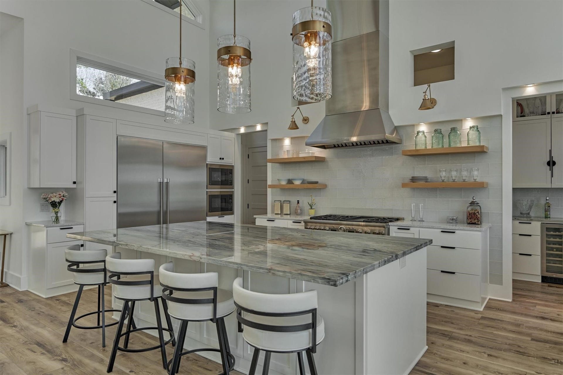 9228 Lake Conroe Drive, Conroe, TX 77304 Wall sconces and accent lighting highlight the full glass tile backsplash wall and wood shelving. The kitchen also features an oversized refrigerator and freezer and two microwaves. Just beyond this view are the pantry to the left and bar area to the right.