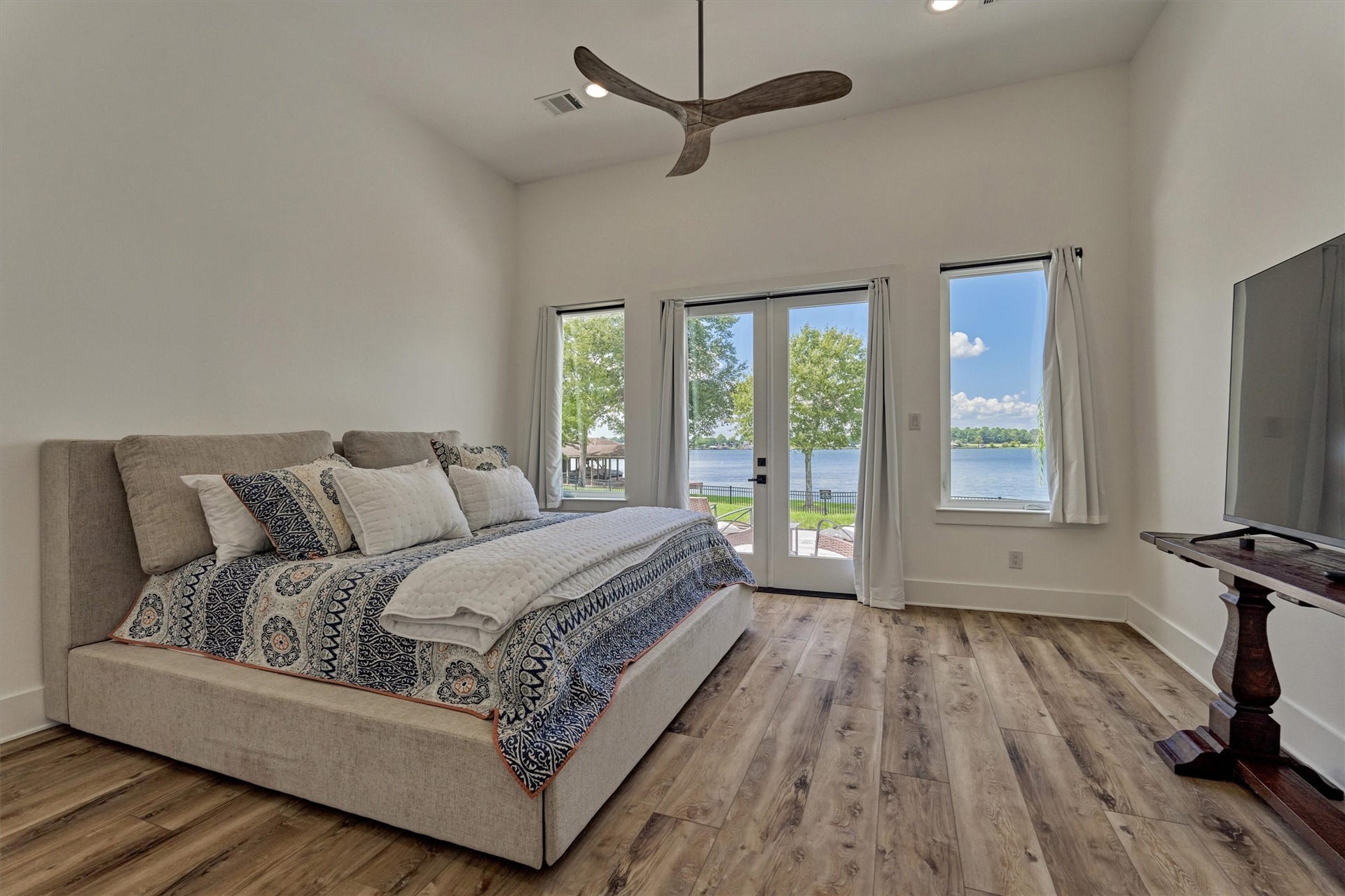9228 Lake Conroe Drive, Conroe, TX 77304 The primary bedroom offers a fresh, serene vibe with light finishes, a high ceiling, and double glass doors that open to the back patio.