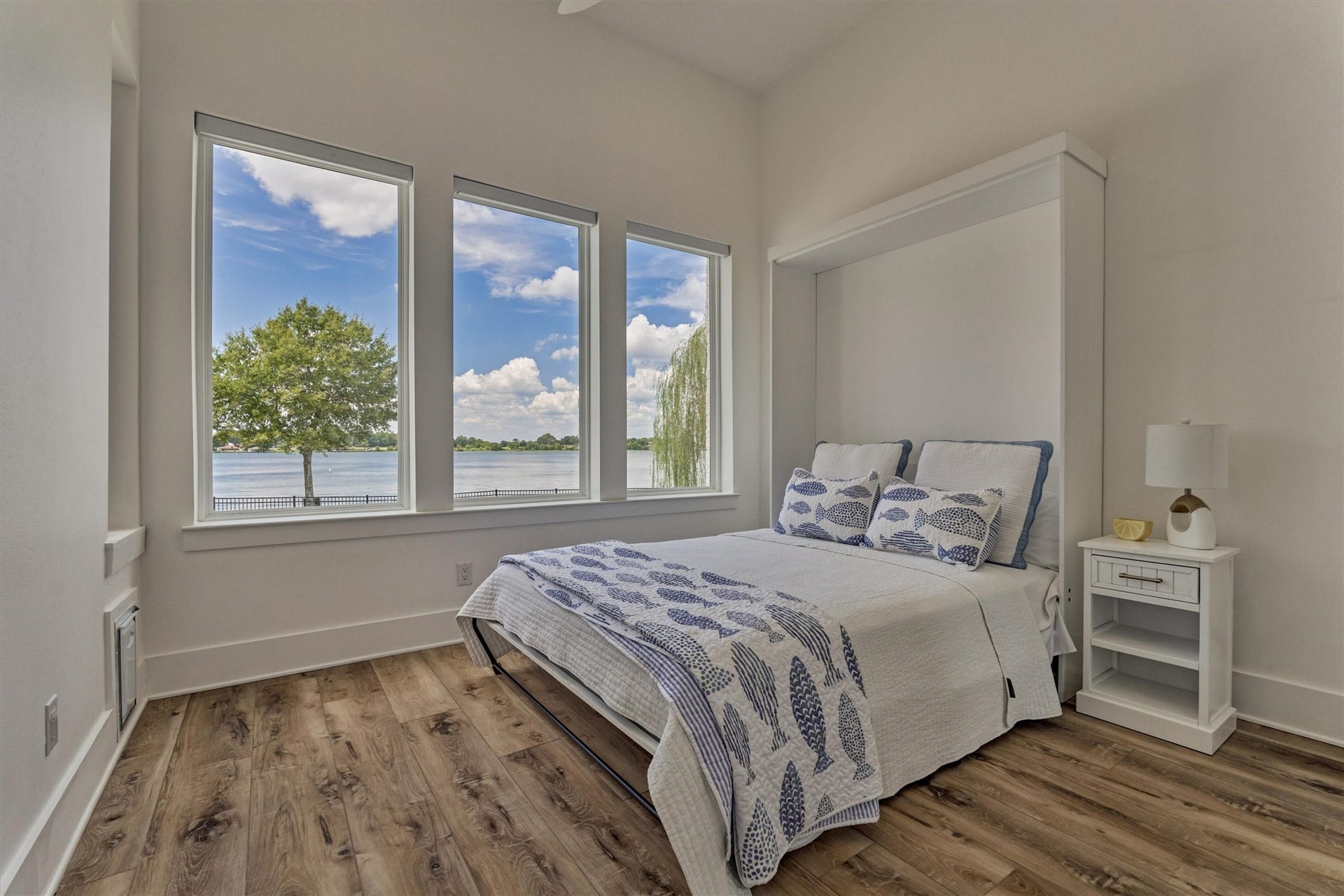 9228 Lake Conroe Drive, Conroe, TX 77304 The third guest bedroom offers a wall of windows with stunning lake views, filling the room with natural light. It currently holds a Murphy bed (virtually staged with bedding), adding versatility to the space. A full bath is conveniently located just off of this room.