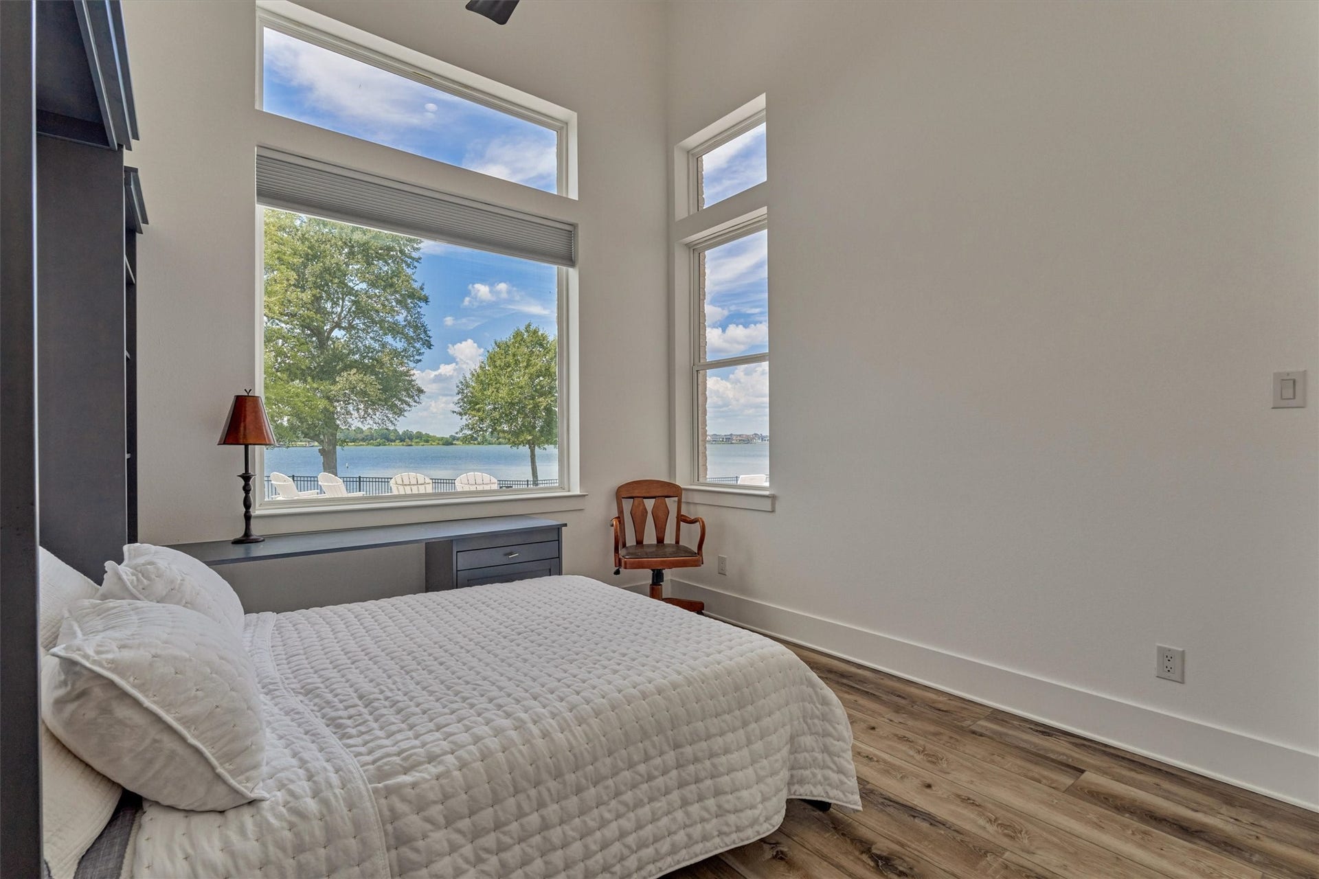 9228 Lake Conroe Drive, Conroe, TX 77304 The first guest bedroom is set up with a desk and Murphy bed. Large windows provide a scenic view of the lake while high ceilings add to the room's airy feel.