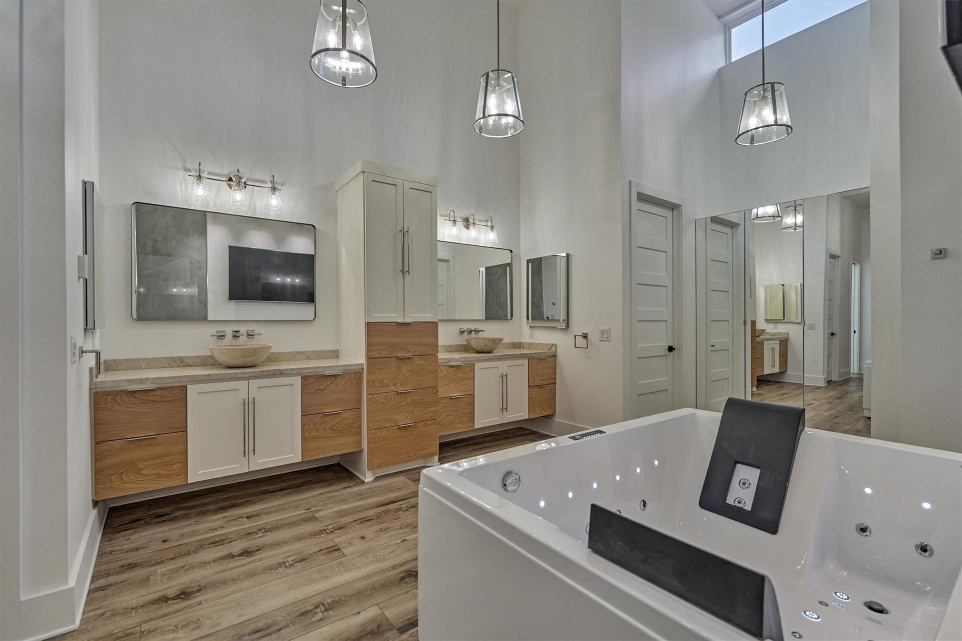 9228 Lake Conroe Drive, Conroe, TX 77304 The coastal modern theme is extended into the primary bath by way of the warm wood tones in the built-in cabinetry, coastal style lighting and modern style mirrors and fixtures. Outlets are located in the center storage piece for convenience of keeping hair dryers and other electrical devices plugged in and put away when not in use.