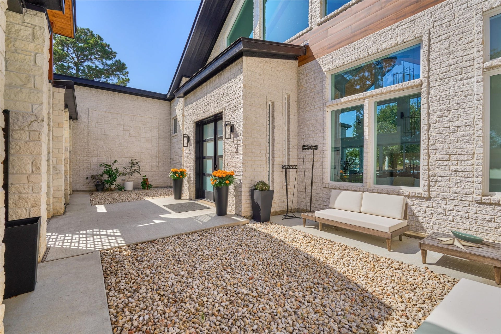 9228 Lake Conroe Drive, Conroe, TX 77304 River rock accents along the courtyard walkway add texture and visual interest, complementing the homes distinctive design.