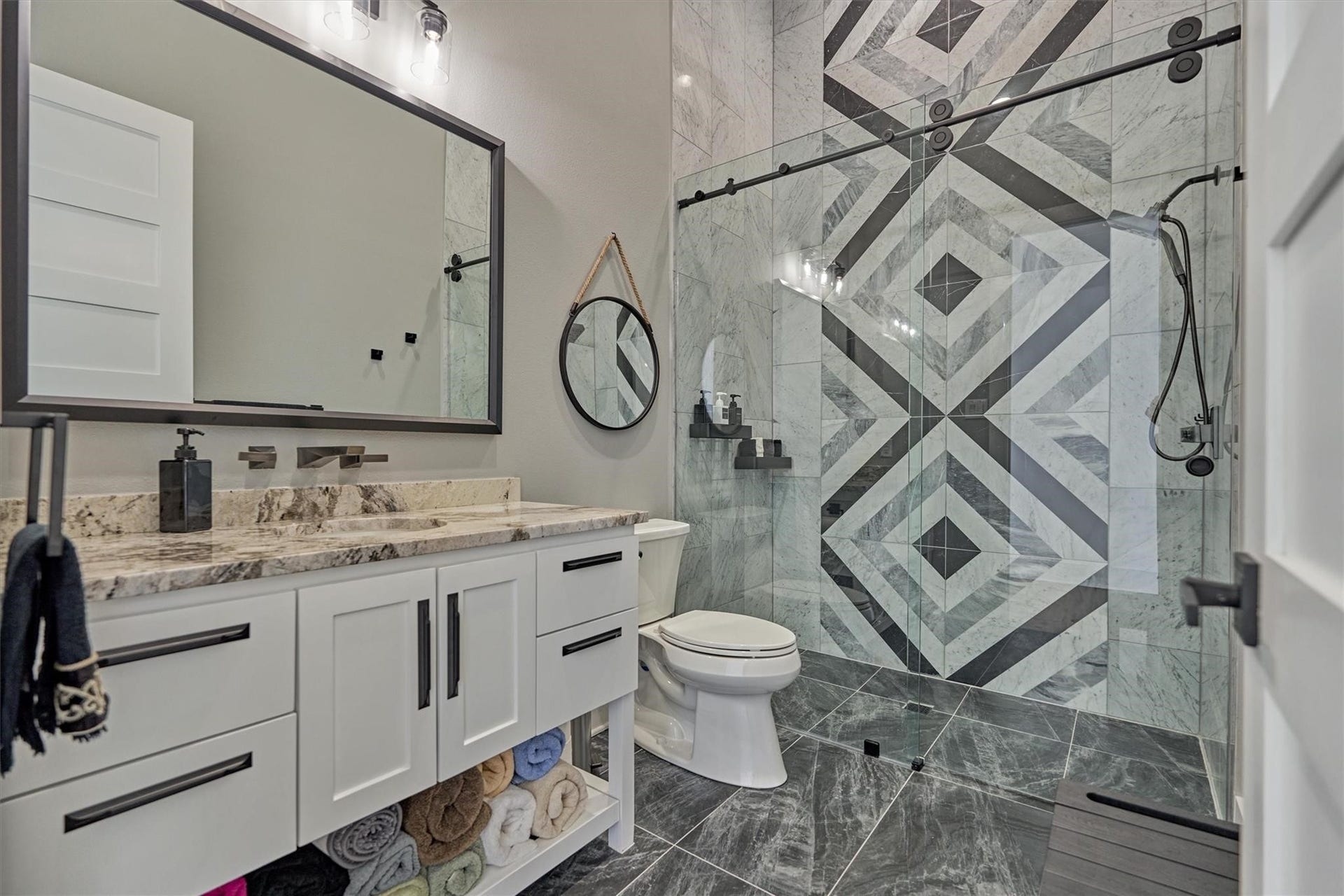 9228 Lake Conroe Drive, Conroe, TX 77304 Sleek and modern is the tone for this guest bath featuring a striking marble tile design in the walk-in shower with a seamless sliding glass door. The vanity features a granite counter, contemporary faucet and mirror, which add the perfect finishing touches to the space.