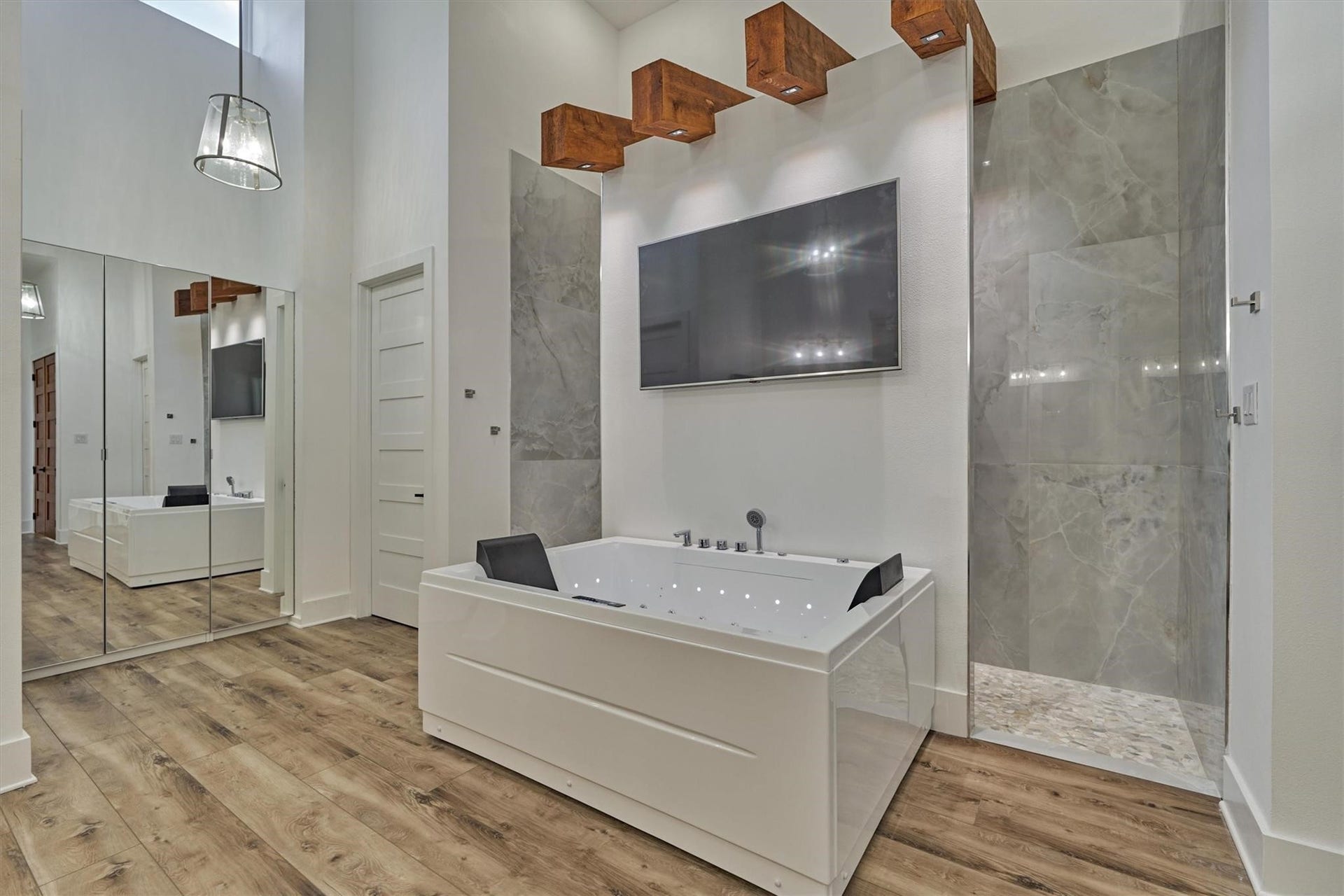 9228 Lake Conroe Drive, Conroe, TX 77304 Rustic wood beams accent the focal point of this primary bath- the two-person spa. Just beyond is a walk-through shower, both enhanced by ambient lighting that create a spa-like atmosphere.