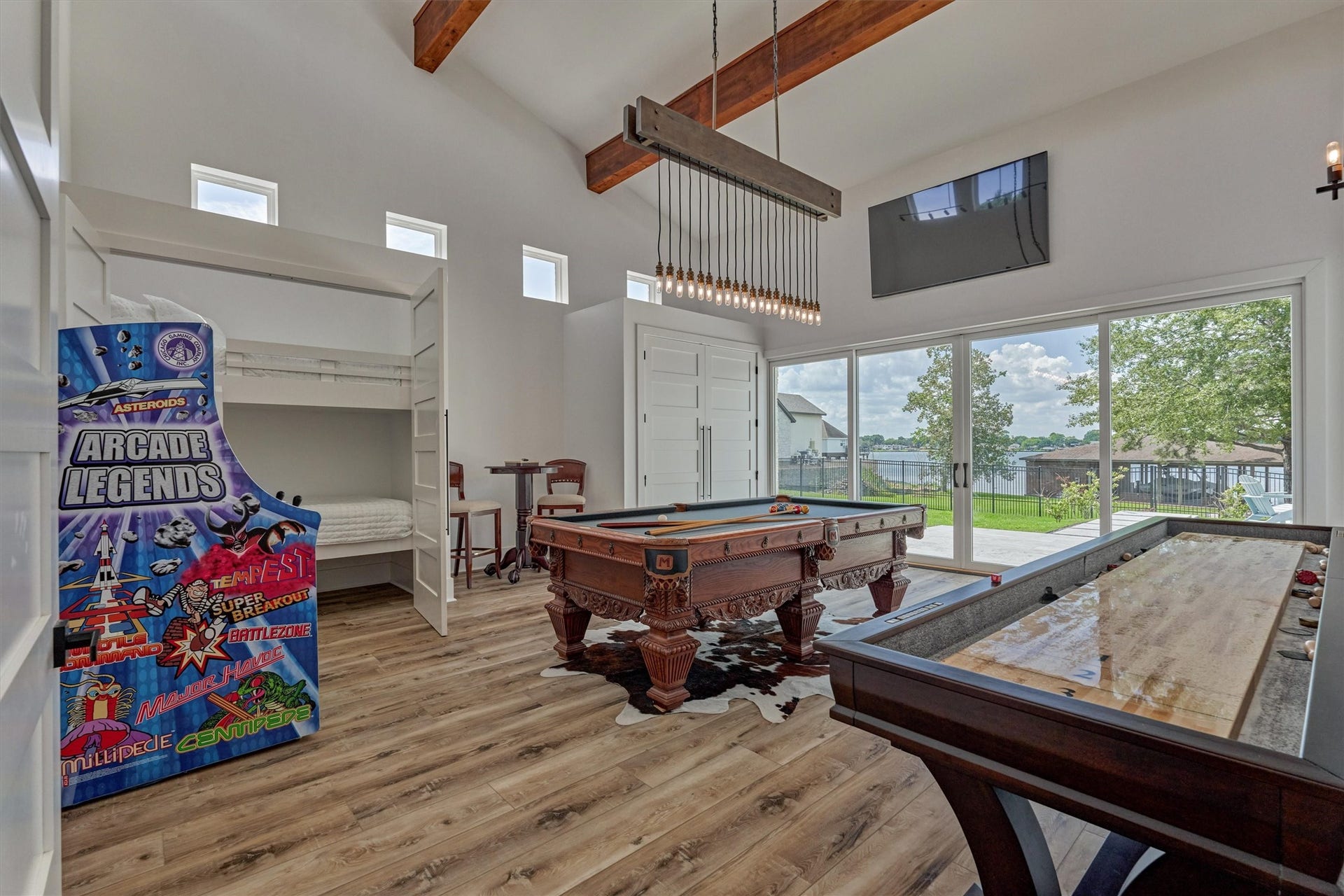 9228 Lake Conroe Drive, Conroe, TX 77304 Accented with wood beams and transom windows, the game room offers a refined rustic vibe. Large windows and sliding glass doors offer a view of the lake while a marble patio beyond provides an ideal space for outdoor entertaining.