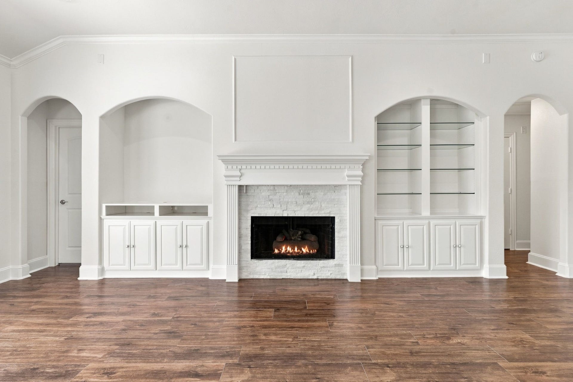 33211 Woodton Court, Fulshear, TX 77441 A closer look at the gas-log Fireplace showcases the beautiful mantel with detailed dental molding and the perfect space above for a large-screen TV. Built-in shelving on each side provides an ideal place to display your favorite dcor and treasured pieces, with an additional option for a TV on the left side of the fireplace. The door to the left leads to the private Primary Suite, while the archway to the right leads to the Secondary Bedrooms and Full Bath.