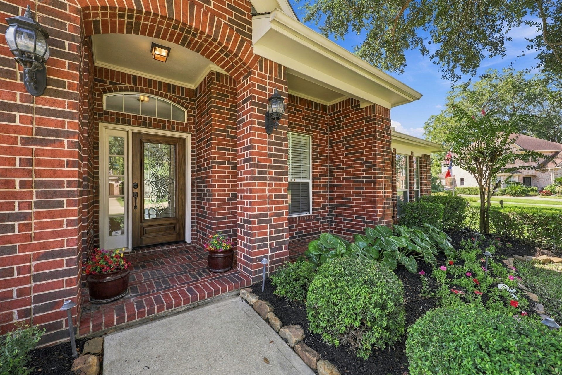 33211 Woodton Court, Fulshear, TX 77441 The covered Front Porch offers an inviting welcome with beautiful brick flooring, elegant black coach lights, and a gorgeous leaded-glass wood front door that adds timeless charm and character to the home.