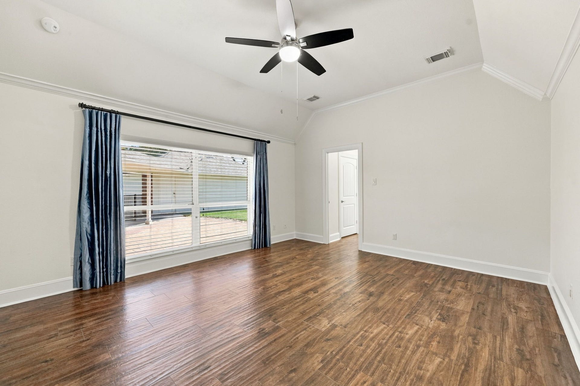 33211 Woodton Court, Fulshear, TX 77441 The spacious Primary Suite easily accommodates a king-size bed with two side tables, along with a comfortable seating area. The room features beautiful wood-look tile flooring, elegant crown molding, 5-inch baseboards, two large windows dressed with designer drapes and 2-inch blinds, a 5-blade ceiling fan, and beautiful views overlooking the back patio.