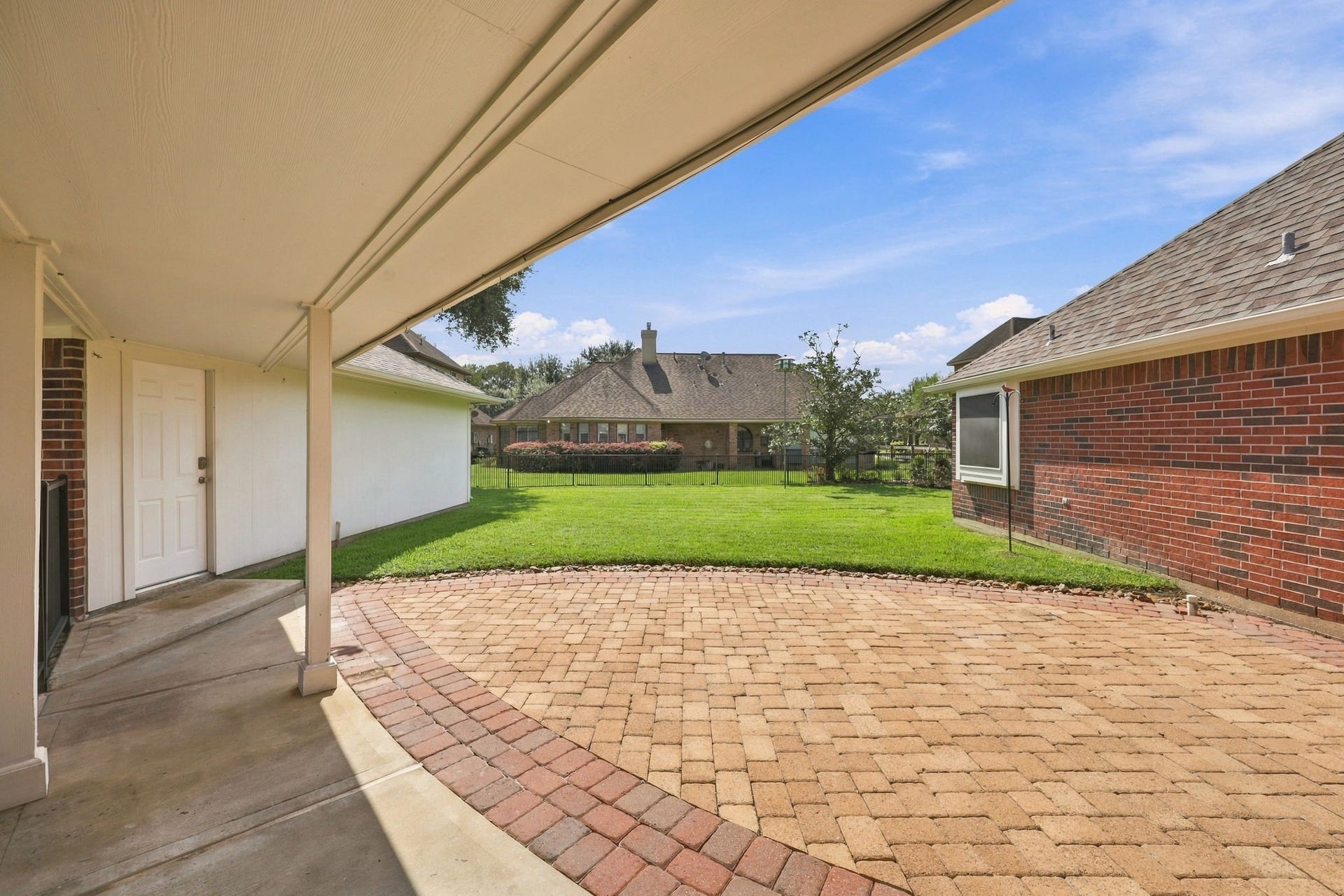 33211 Woodton Court, Fulshear, TX 77441 Lets step outside! This beautiful home is situated on an oversized 11,021-square-foot lot. This view showcases the covered breezeway connecting the detached garage to the home, providing convenient protection from the elements when bringing in groceries or heading to the house on a rainy day. The extended back patio features paver flooring and offers plenty of space for outdoor tables, chairs, and seating, creating an inviting setting for relaxing and entertaining.
