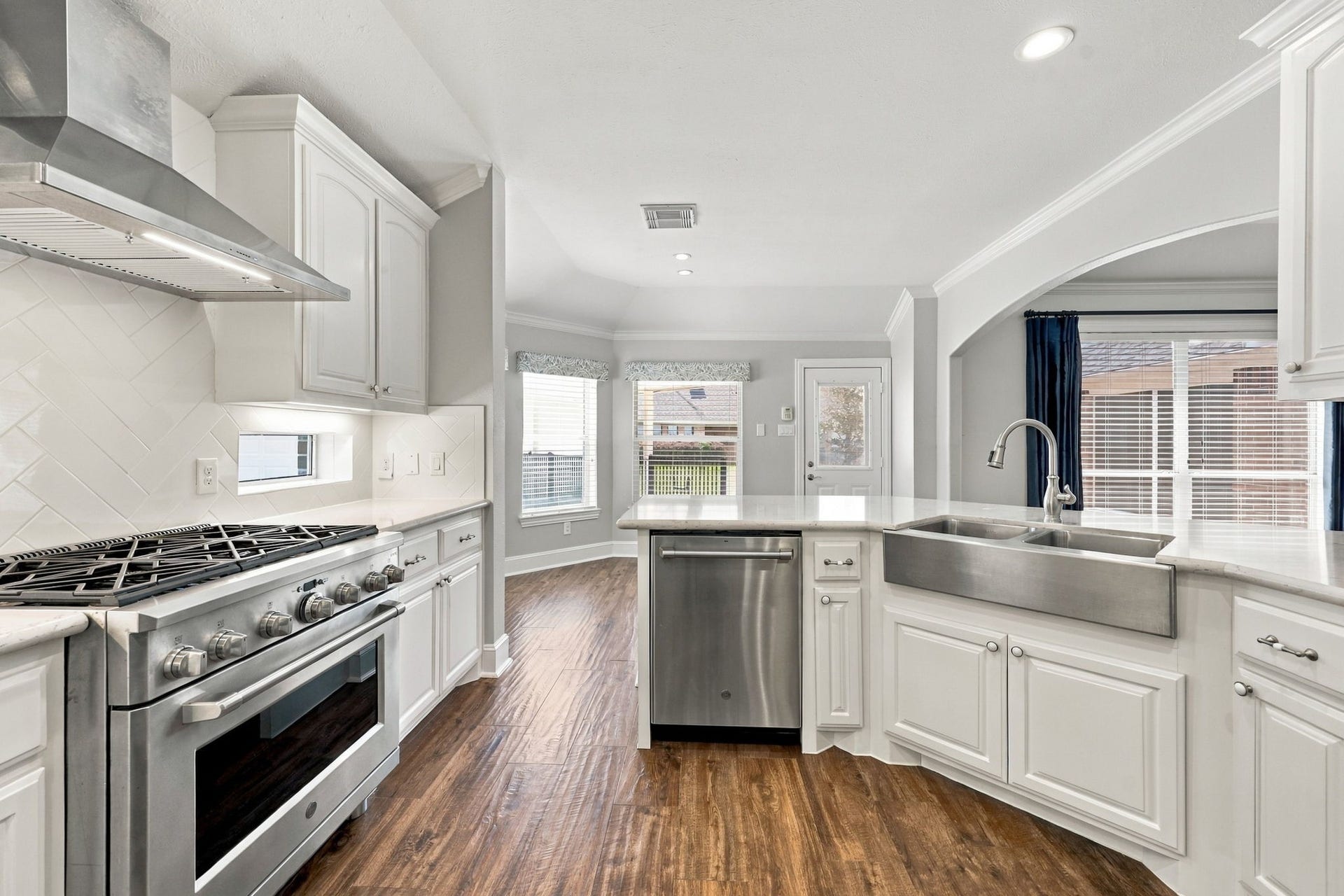 33211 Woodton Court, Fulshear, TX 77441 The farmhouse stainless steel sink, paired with a sleek gooseneck chrome faucet, adds charm and character to the Kitchen and is perfectly situated within the large Breakfast Bar, creating a functional and inviting space for meal preparation and casual dining.