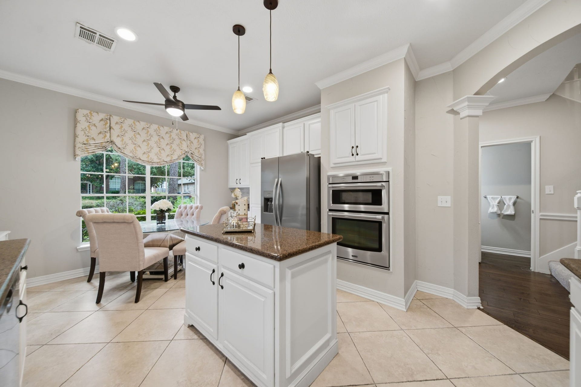 99 E Sterling Pond Circle, The Woodlands, TX 77382 White cabinetry, stainless steel microwave and oven, and pendant lighting complement this inviting kitchen. The center island provides addional prep and storage space. The adjoining breakfast area offers natural light and views of the greenery outside. Custom window treatments nicely frame the large window.