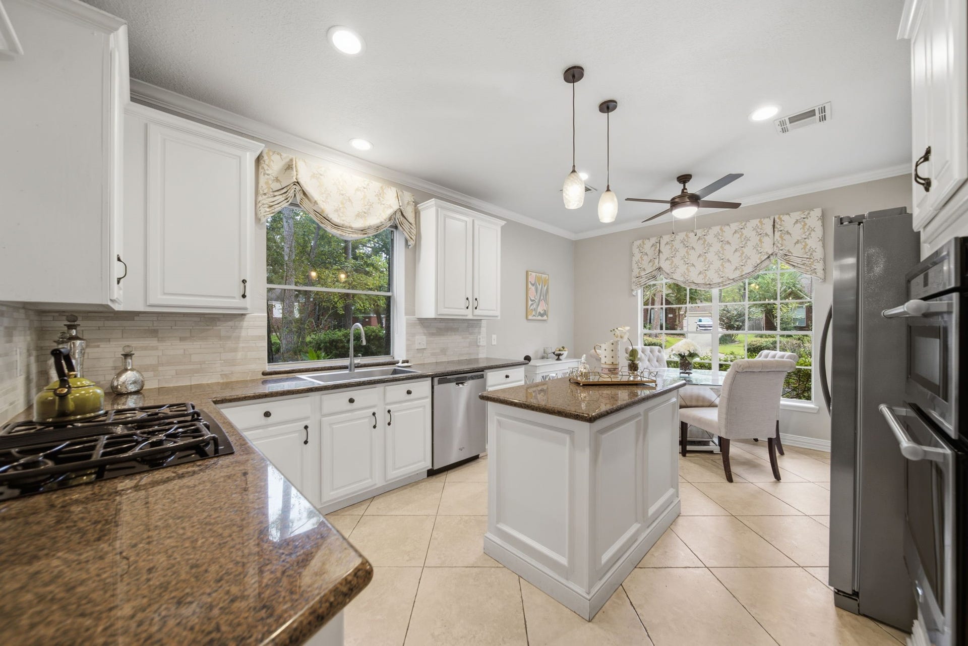 99 E Sterling Pond Circle, The Woodlands, TX 77382 Bright and inviting kitchen featuring elegant white cabinetry, sleek countertops, and stainless steel appliances, complete with a cozy breakfast nook overlooking a lush garden.