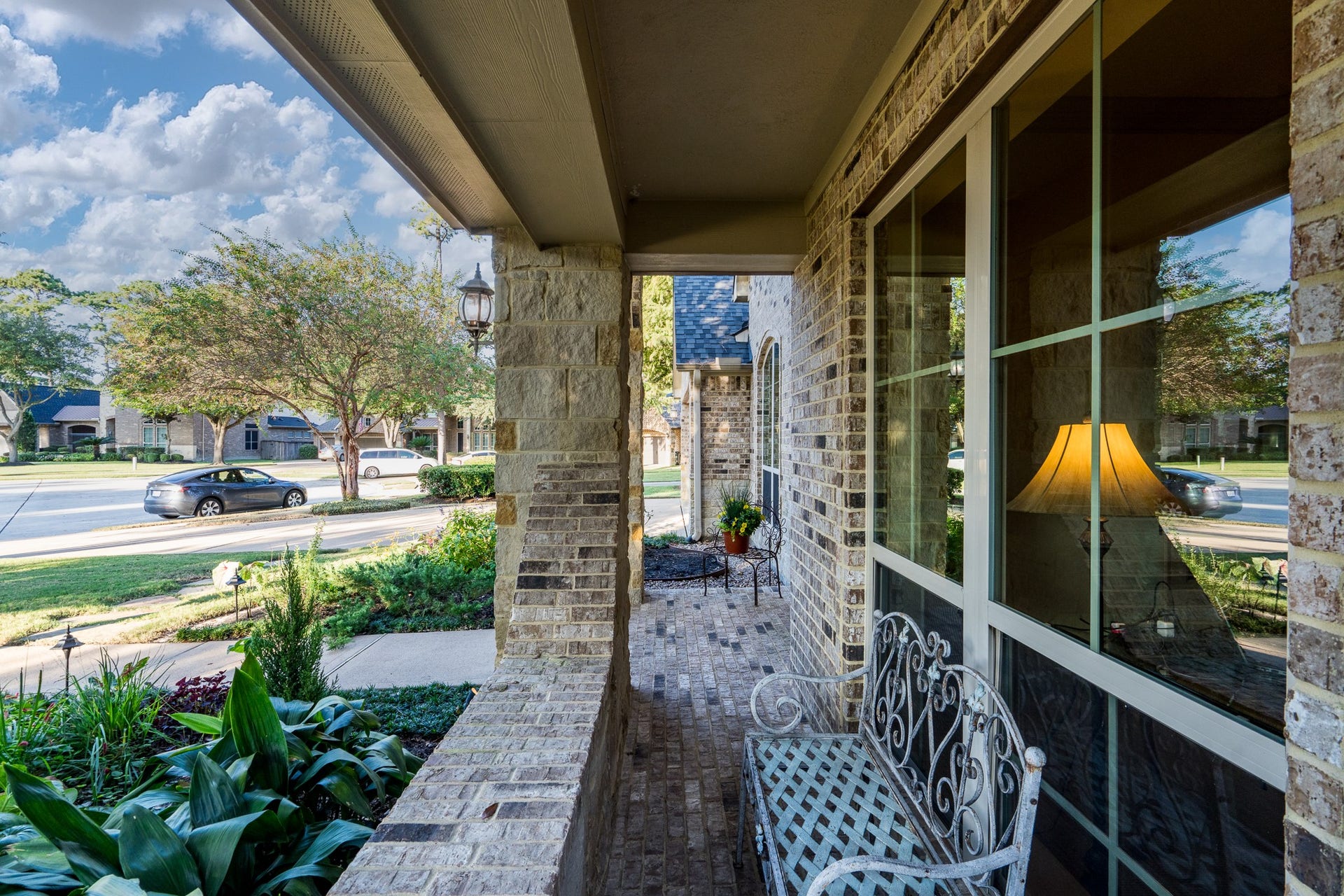 13807 Oak Fair Bend, Cypress, TX 77429 A CHARMING PLACE TO PAUSE AND ENJOY THE BEAUTY OF HOME! This inviting covered front porch features beautiful brick detailing, stately stone columns, and an elegant wrought-iron bench overlooking lush landscaping and the picturesque neighborhood. A peaceful spot to enjoy your morning coffee, welcome guests, or simply savor the timeless charm of this exceptional home!