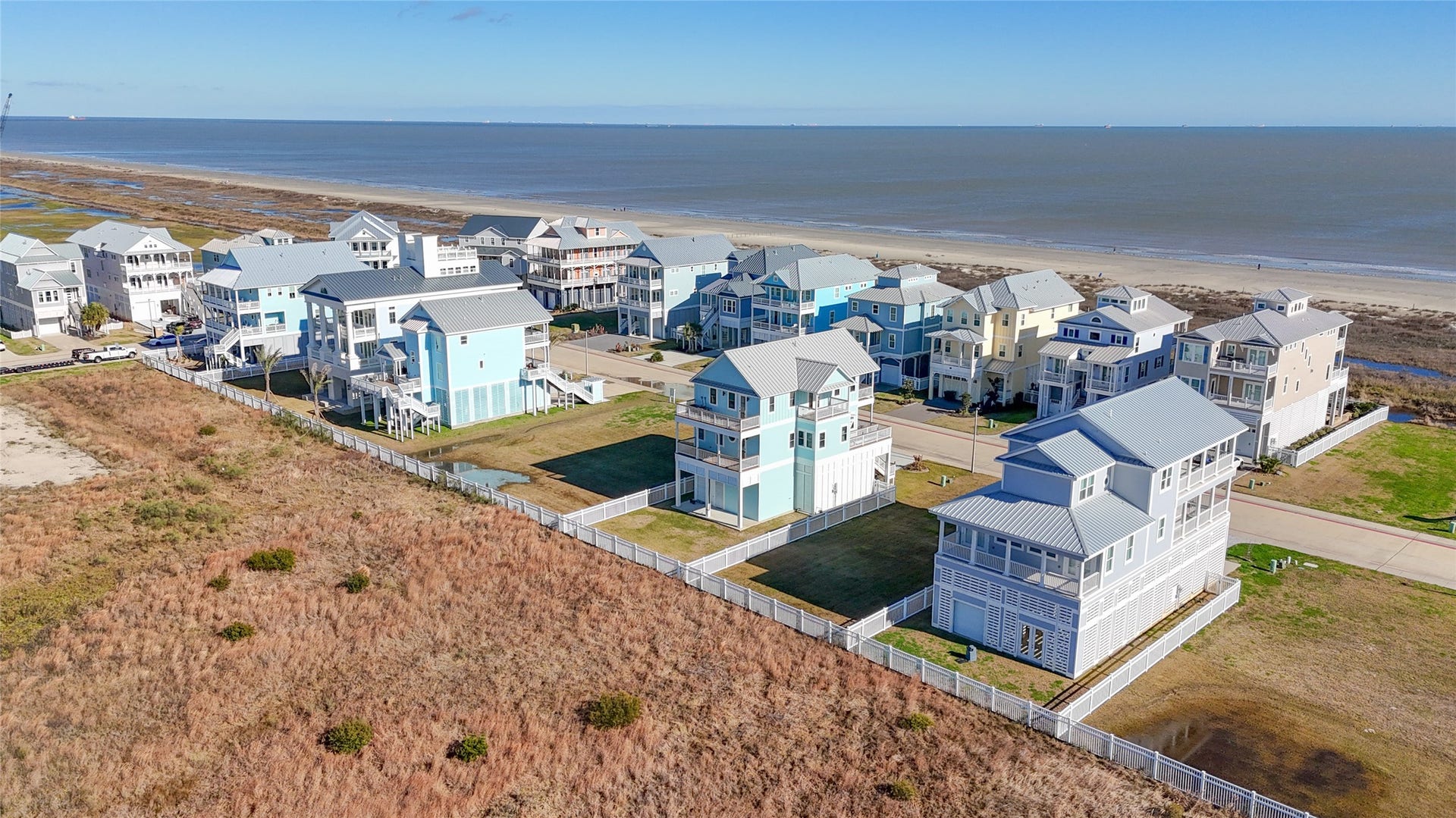 This aerial perspective places the homesite in context with both the Gulf and neighboring residences, demonstrating its desirable second-row location within The Preserve at Grand Beach. The property sits just across the street from beach access and is surrounded by substantial coastal homes, offering an increasingly rare opportunity to build new construction on Galvestons East End while remaining only minutes from The Strand.