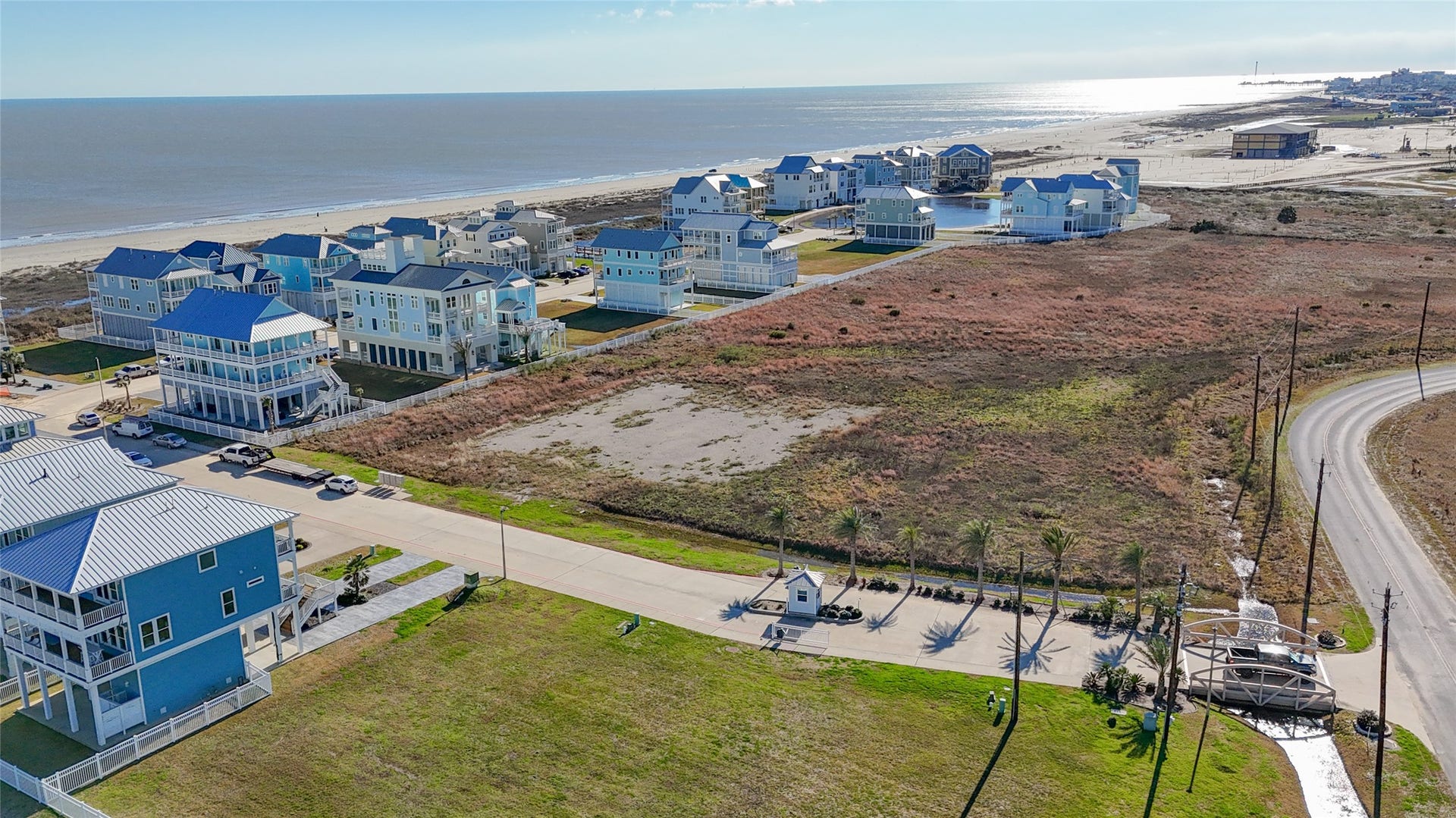 A wider aerial perspective showcases the low-density surroundings beyond the homesite and helps illustrate the property's open western exposure. The absence of an immediate rear residence provides breathing room rarely associated with an in-town Galveston building site and creates an appealing backdrop for rear-facing balconies, outdoor living spaces and windows designed to take advantage of evening light and expansive sunset views.